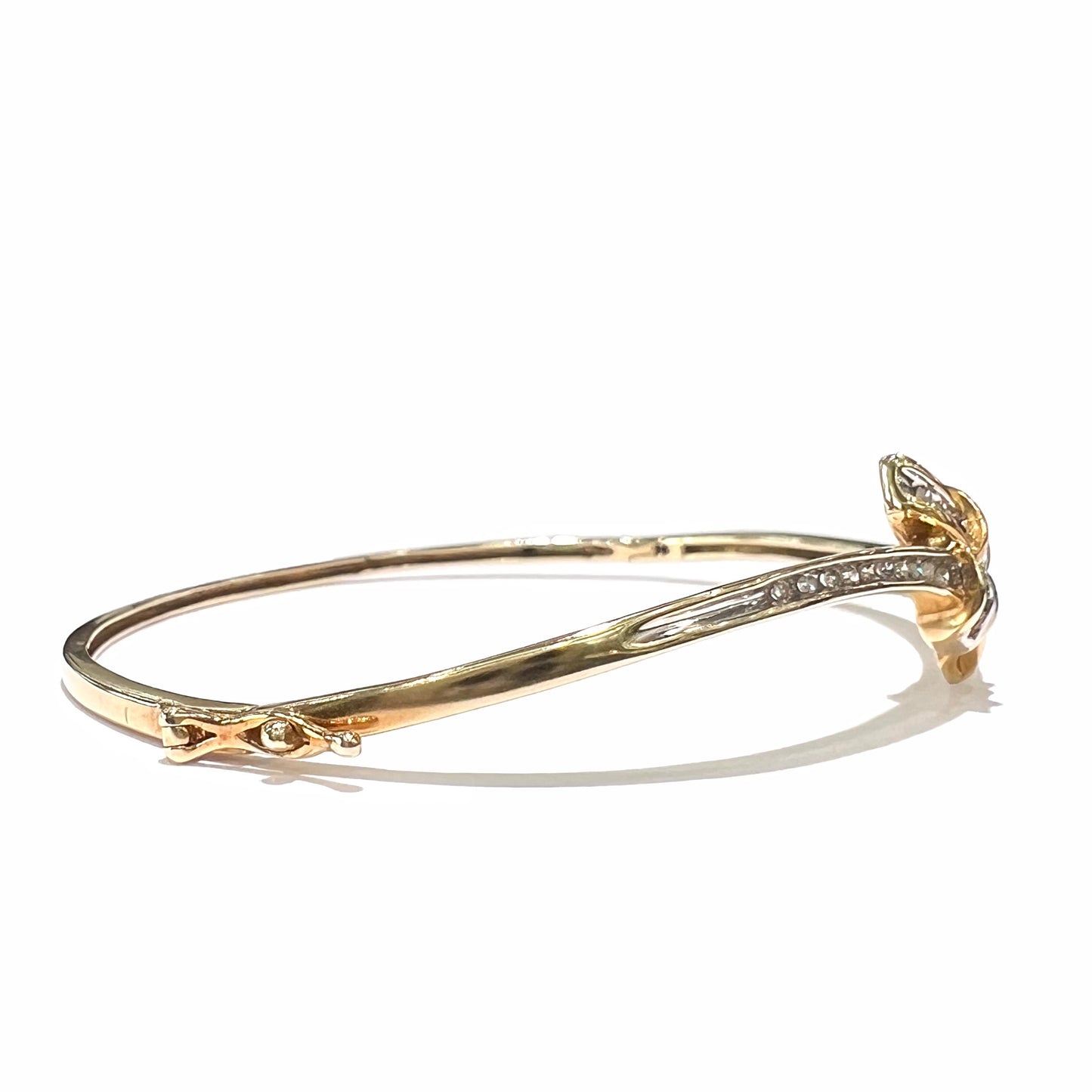 A ladies' knot style yellow gold bangle bracelet set with round and baguette cut diamonds.