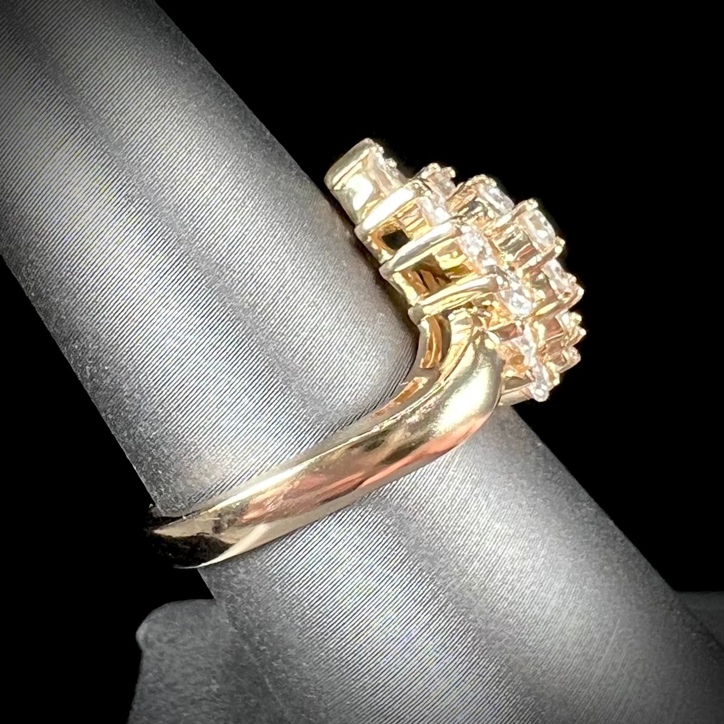 A yellow gold diamond cluster ring set with round, marquise, and baguette cut diamonds.