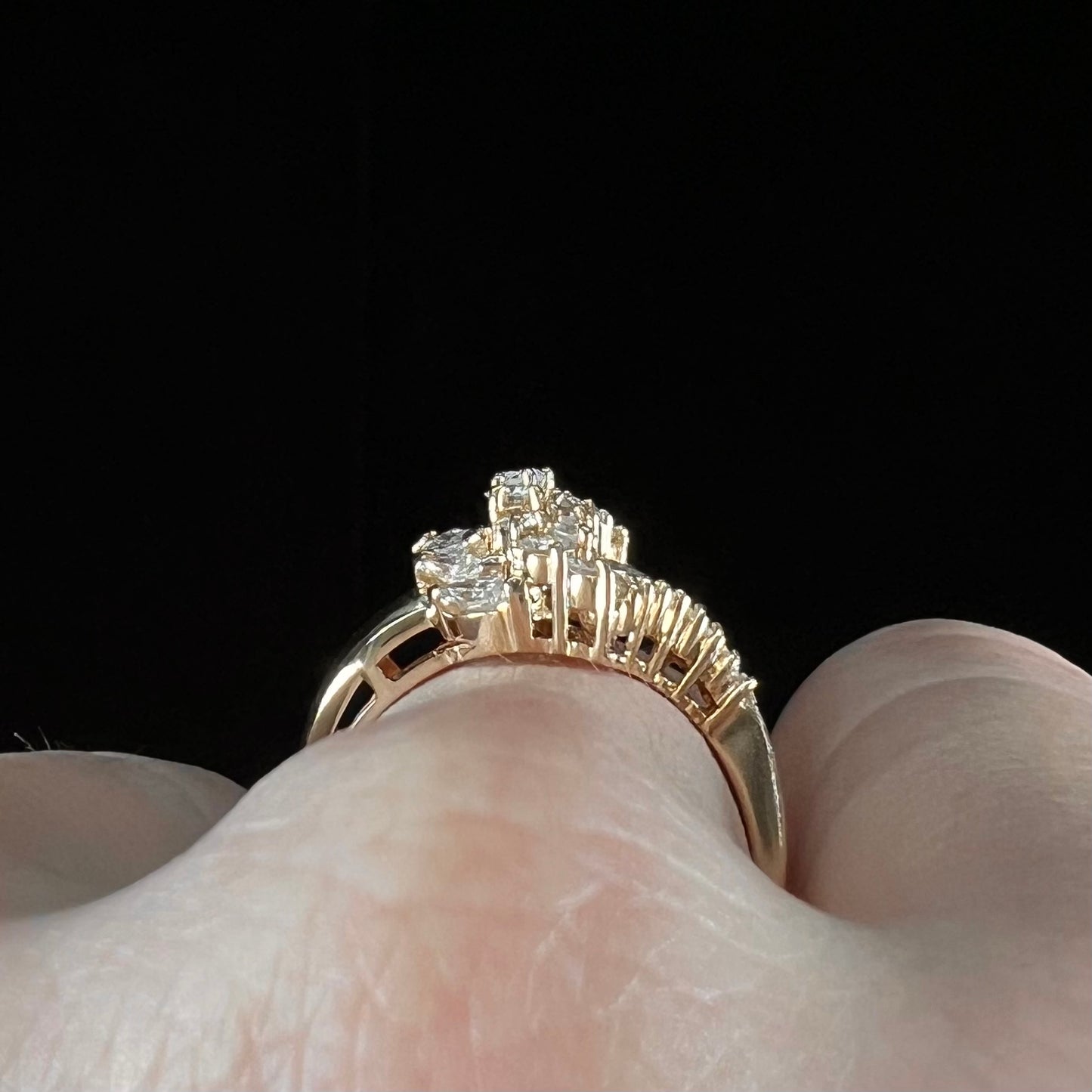 A yellow gold diamond cluster ring set with round, marquise, and baguette cut diamonds.