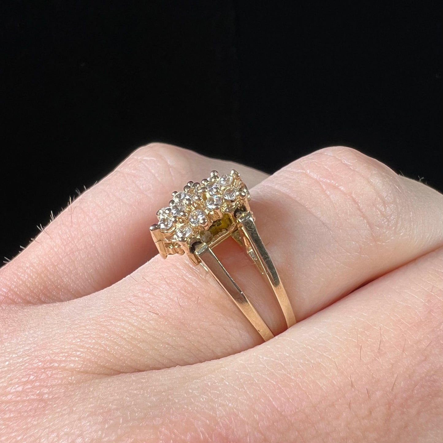 A yellow gold reversible gemstone flip ring. One side of the ring shows a green gemstone, the other shows a cluster of cubic zirconia.