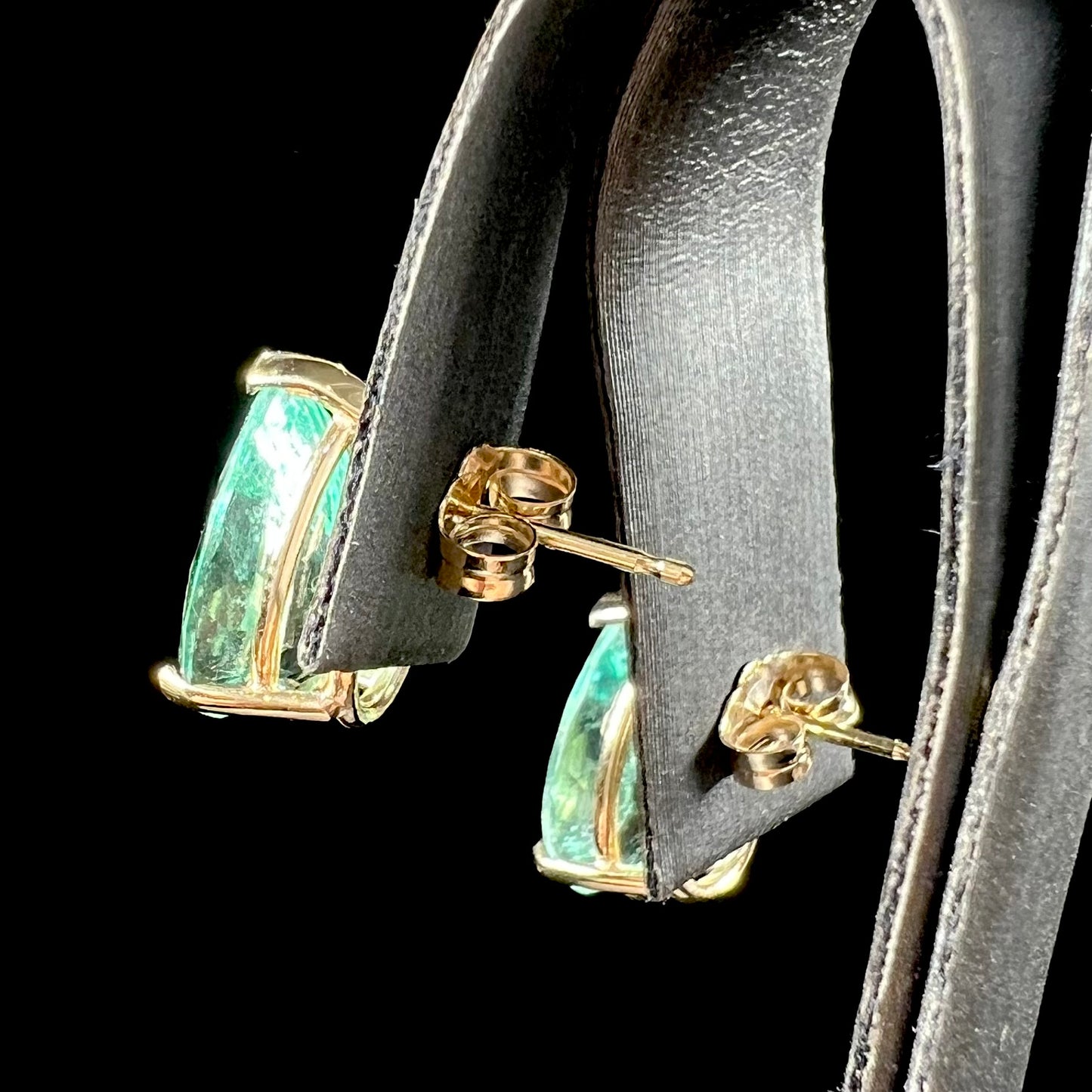 A pair of yellow gold stud earrings set with natural, pear shaped emeralds.