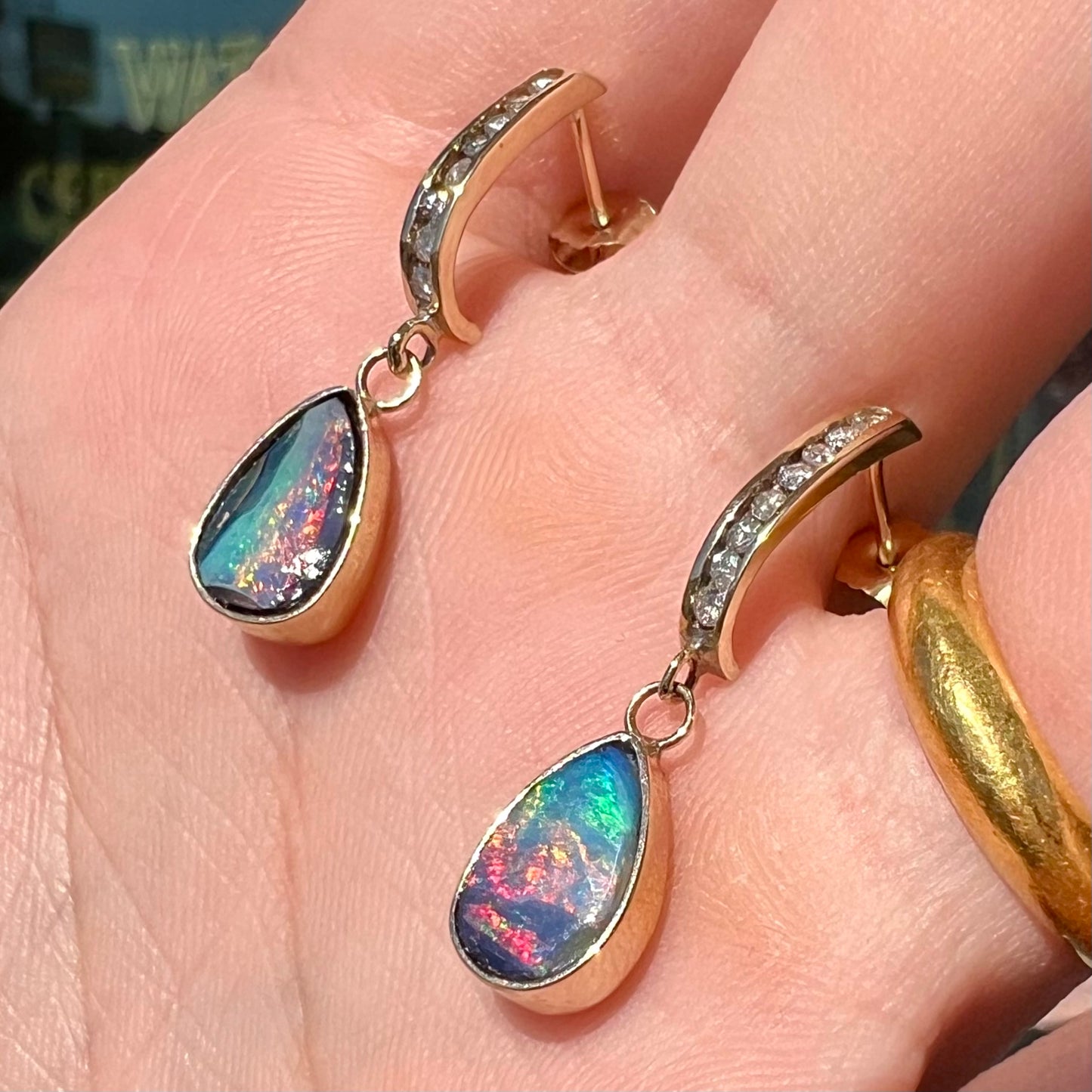 A pair of yellow gold dangle earrings set with natural pear shaped boulder opals and diamonds.