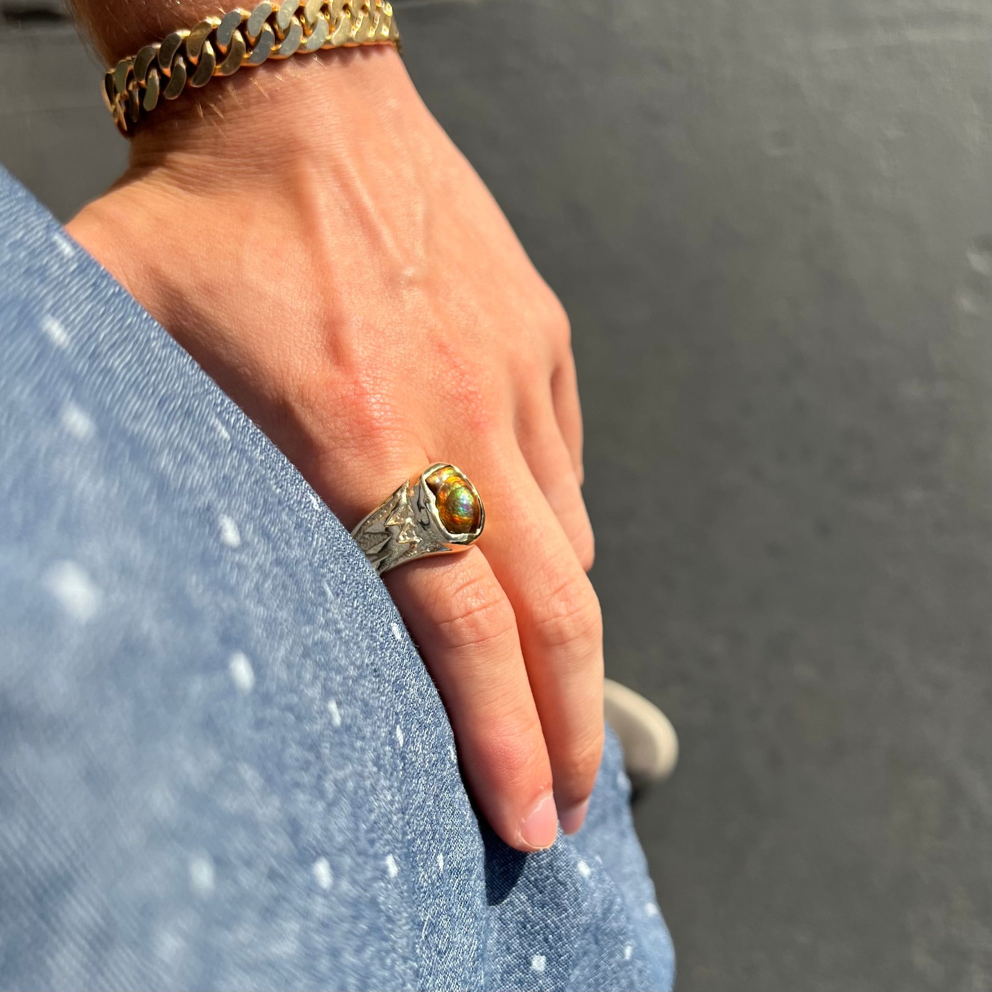 A man's yellow gold solitaire ring set with a freeform shaped Mexican fire agate stone.  The stone has a purple bull's eye pattern.
