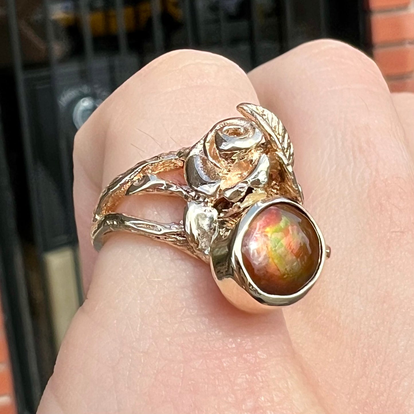 A ladies' yellow gold flower style ring set with an oval cabochon cut fire agate and diamond accents.