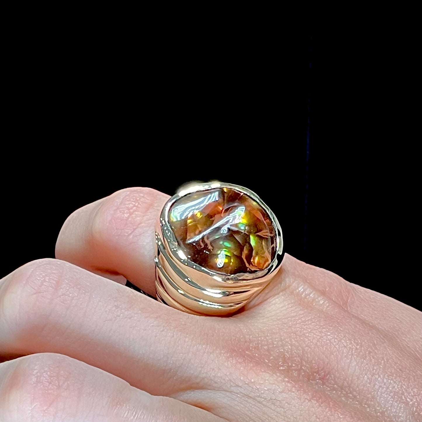 A men's heavy yellow gold ring set with a Mexican fire agate stone and three round brilliant cut diamond accents.