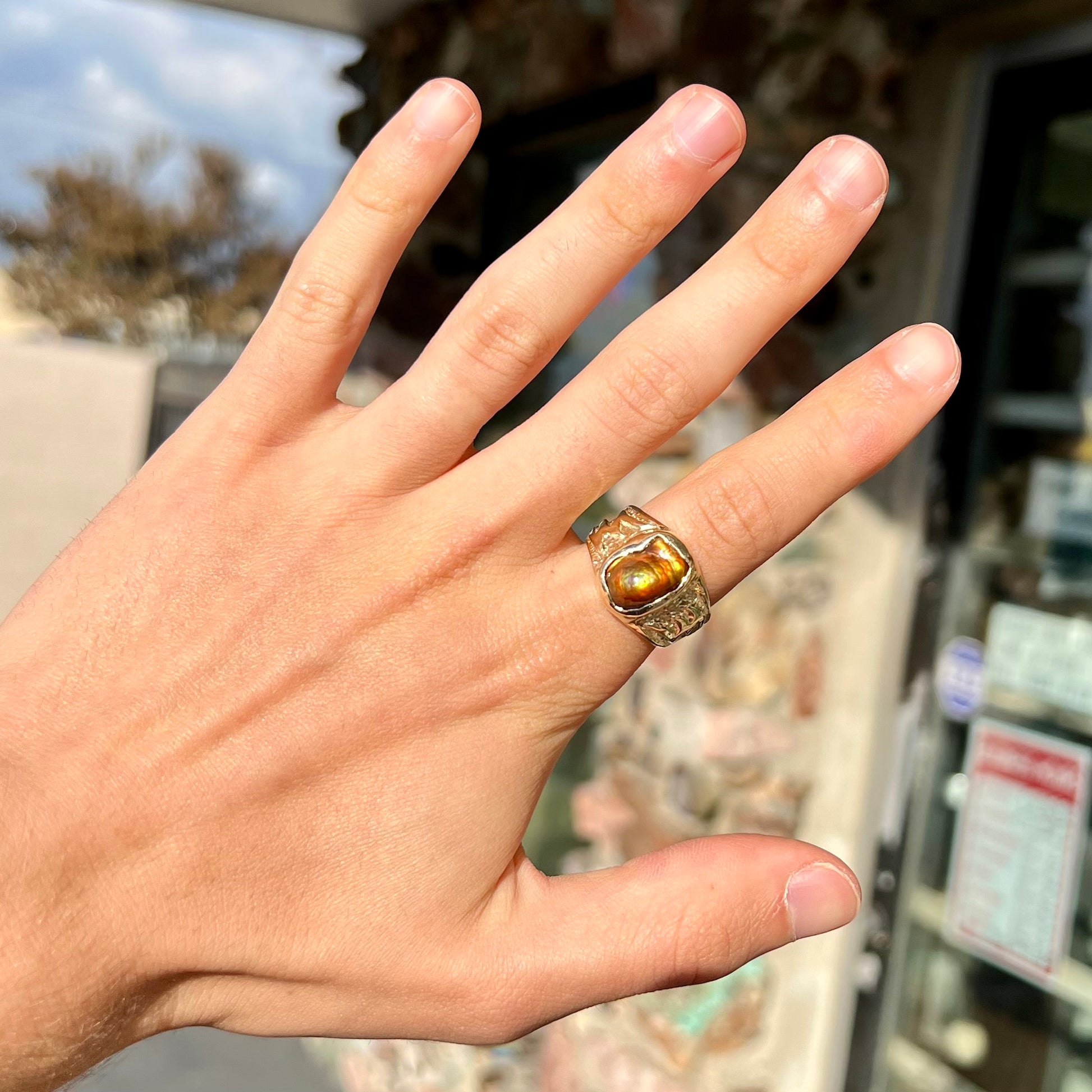 A man's yellow gold solitaire ring set with a freeform shaped Mexican fire agate stone.  The stone has a purple bull's eye pattern.