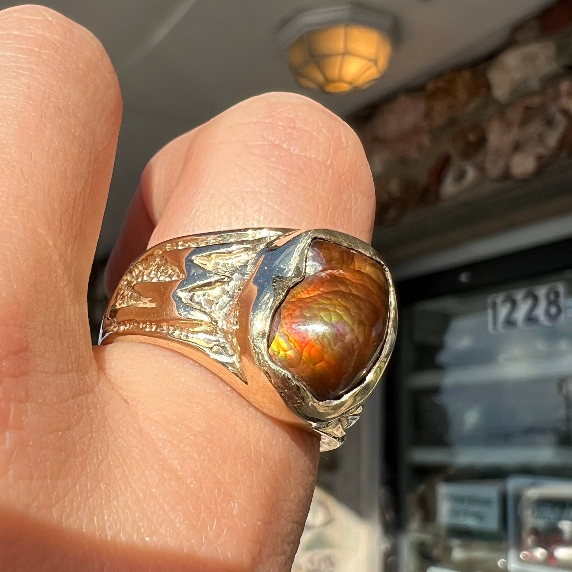 A man's yellow gold solitaire ring set with a freeform shaped Mexican fire agate stone.  The stone has a purple bull's eye pattern.