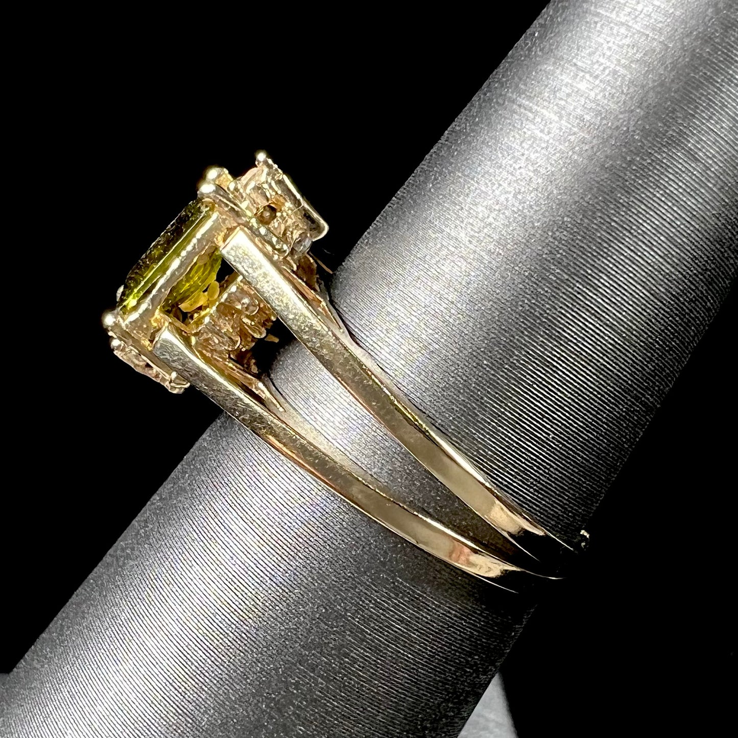 A yellow gold reversible gemstone flip ring. One side of the ring shows a green gemstone, the other shows a cluster of cubic zirconia.
