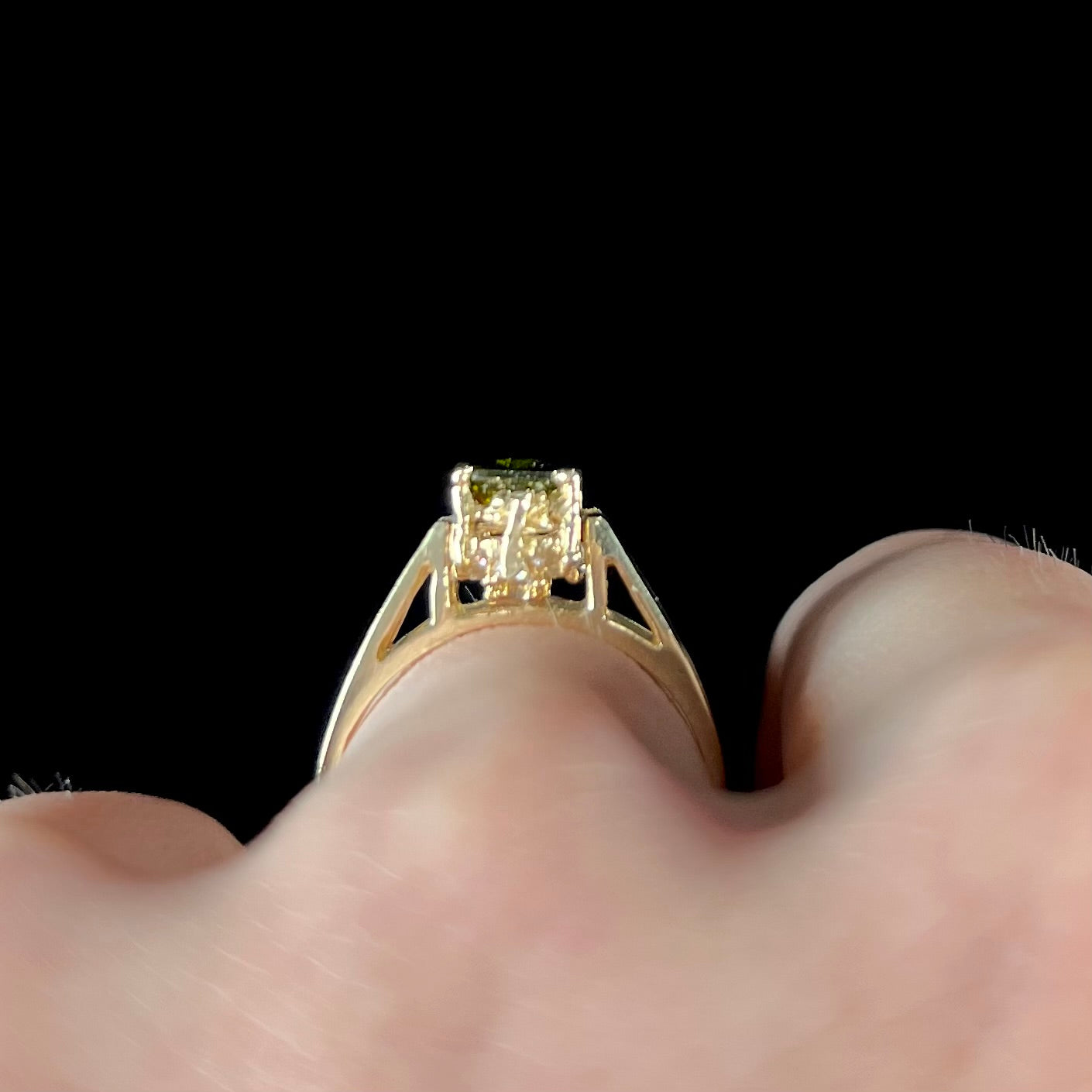 A yellow gold reversible gemstone flip ring. One side of the ring shows a green gemstone, the other shows a cluster of cubic zirconia.