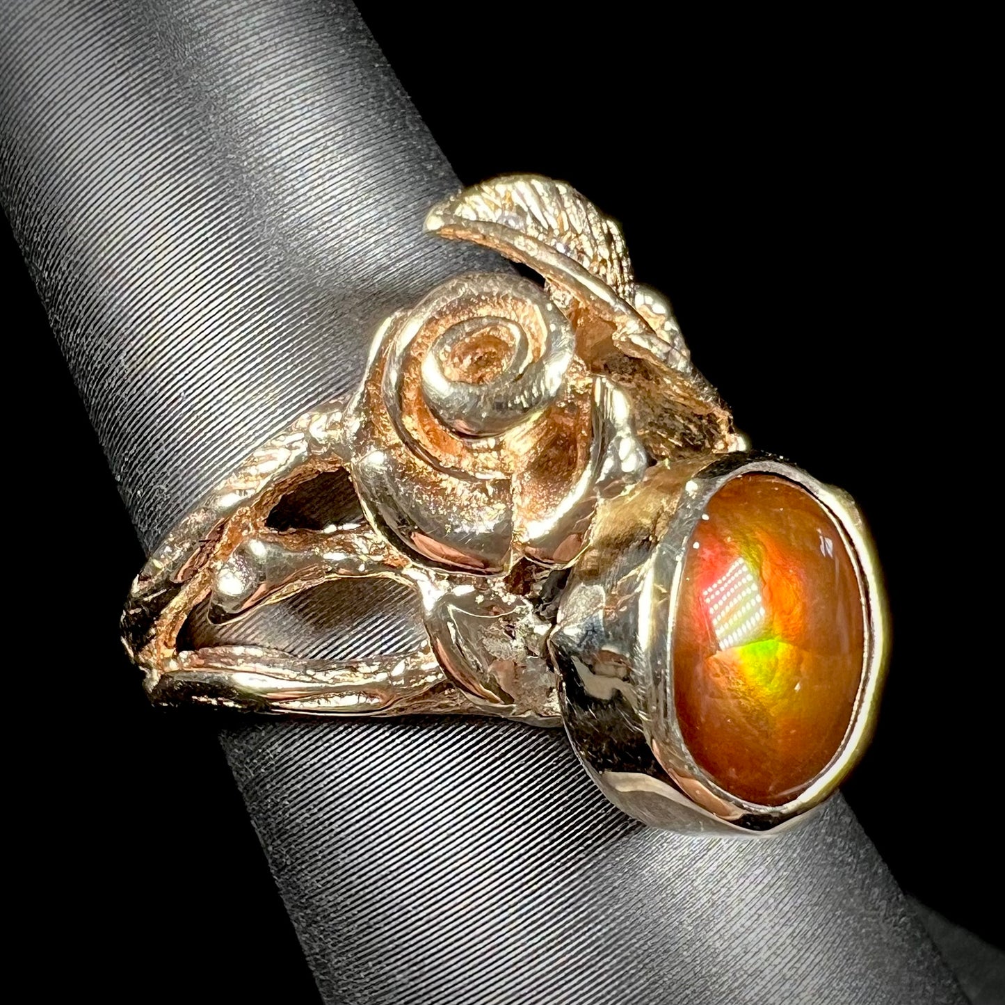 A ladies' yellow gold flower style ring set with an oval cabochon cut fire agate and diamond accents.