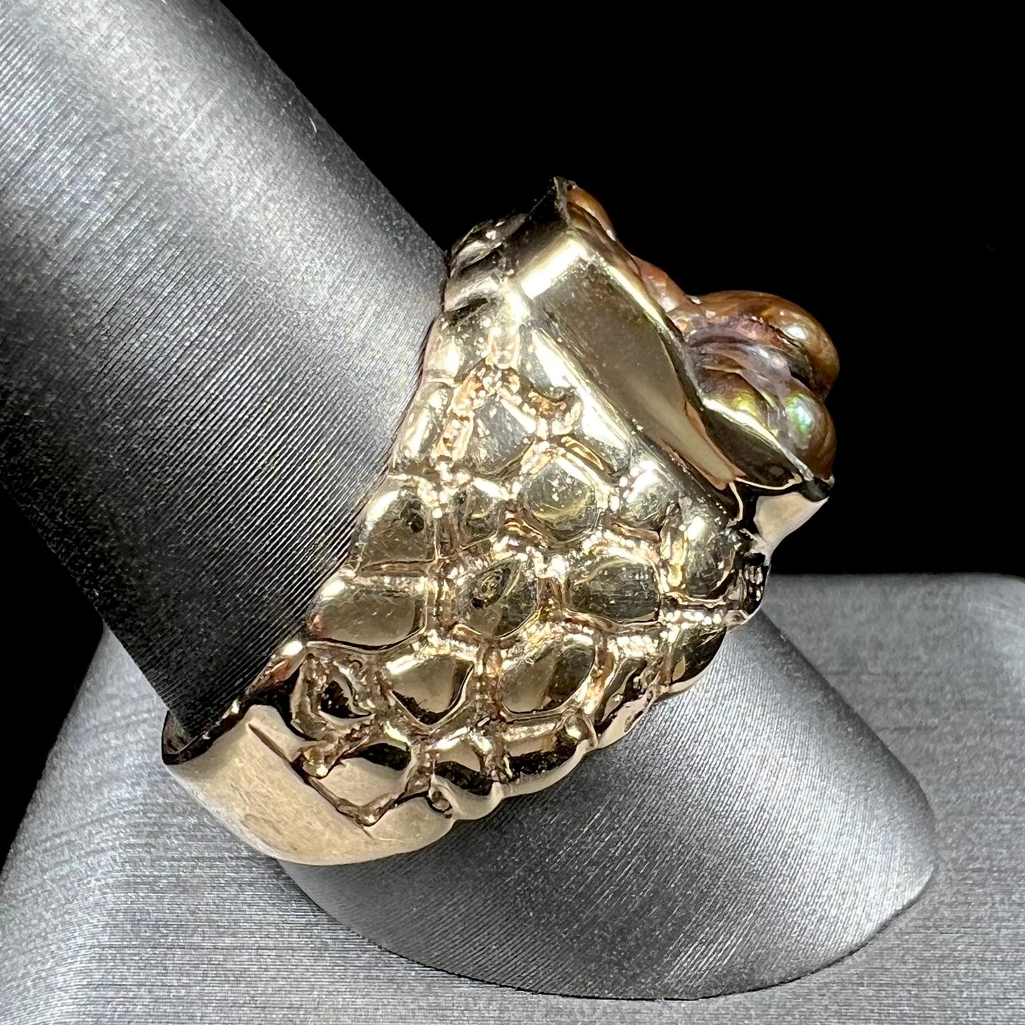 A men's yellow gold, nugget style ring set with a bubbly, California fire agate stone.