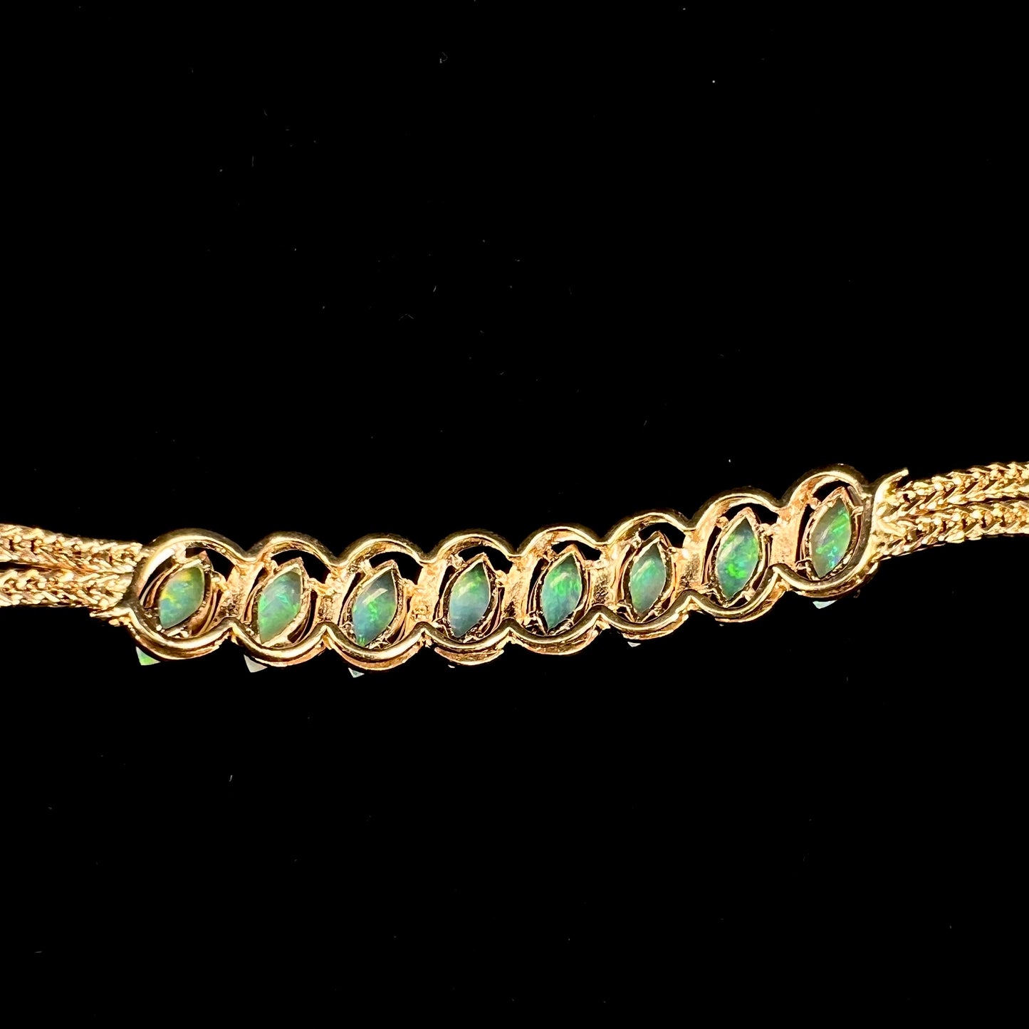 A ladies' yellow gold bracelet prong set with eight natural, marquise cabochon cut opals.