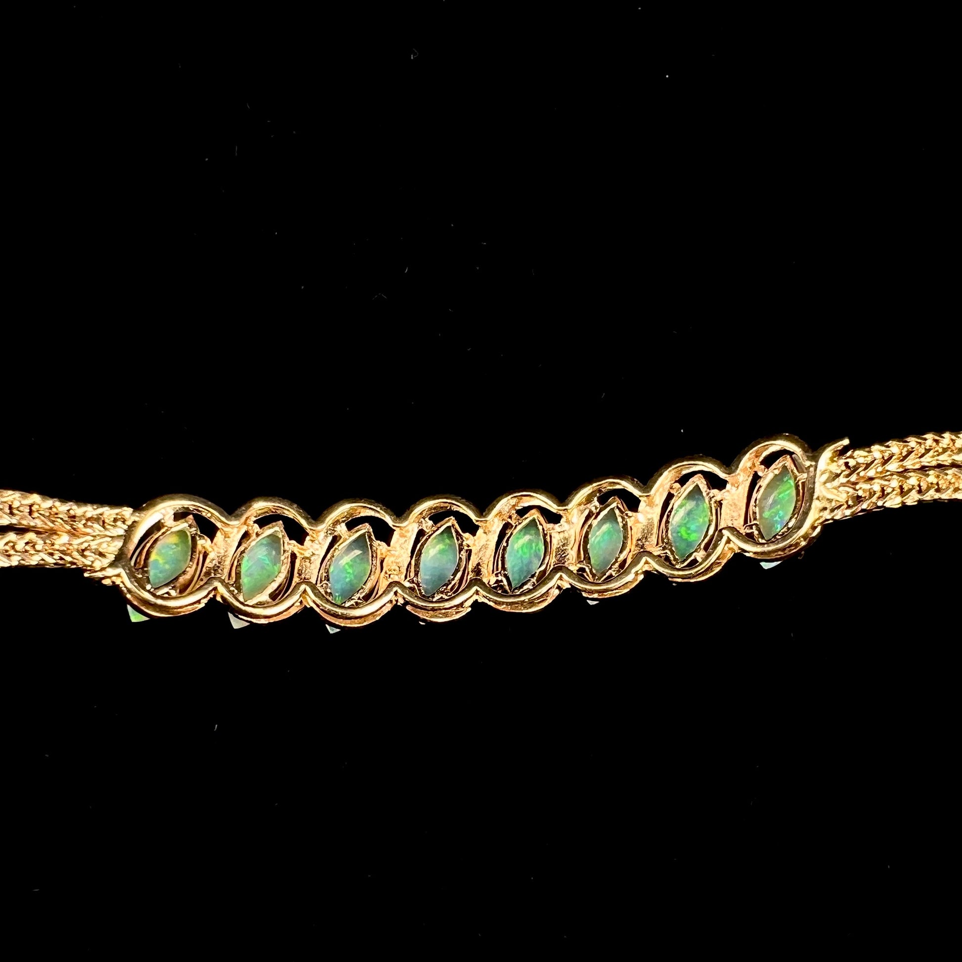 A ladies' yellow gold bracelet prong set with eight natural, marquise cabochon cut opals.