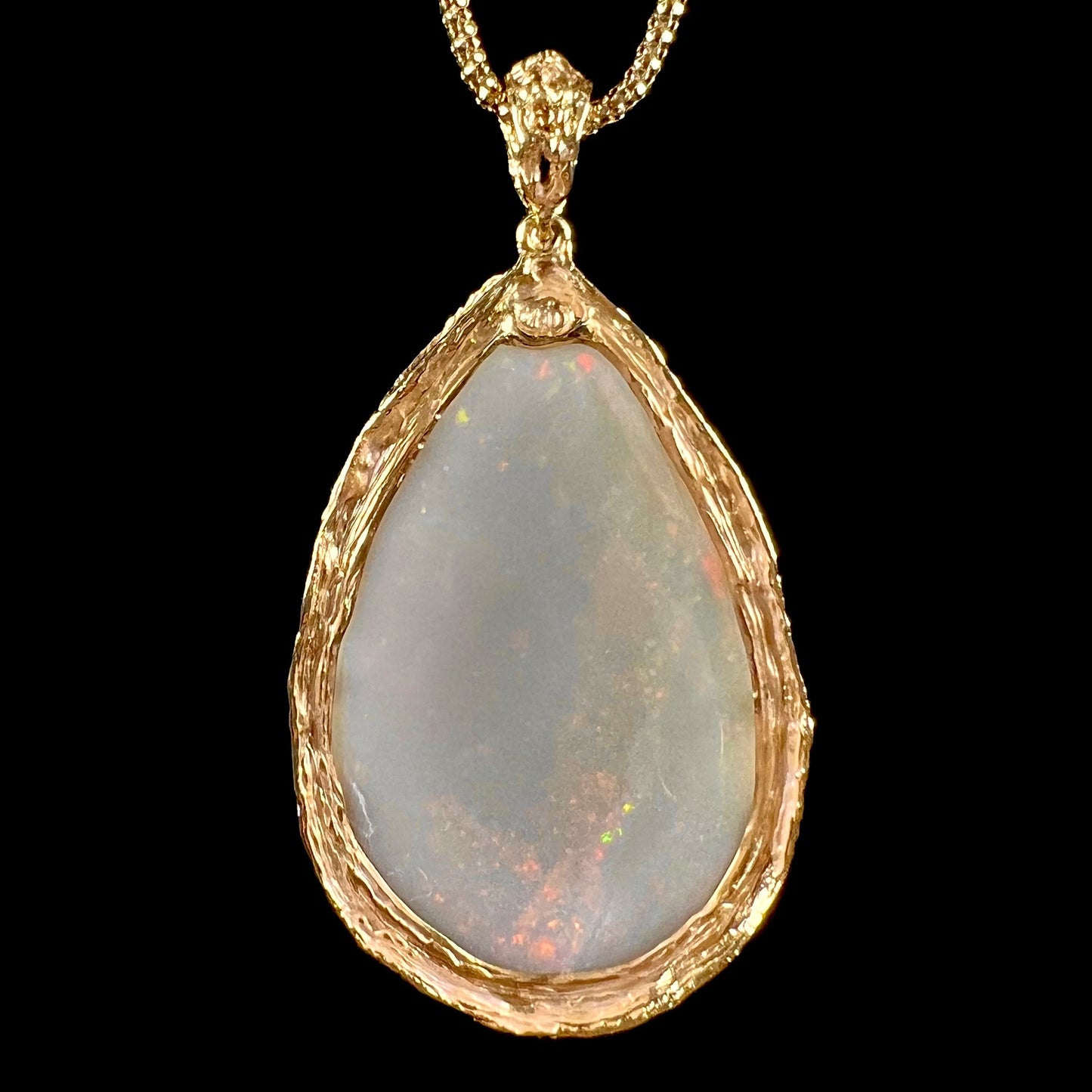 A ladies' natural, pear shaped, gray base Australian opal pendant set in 18 karat yellow gold.