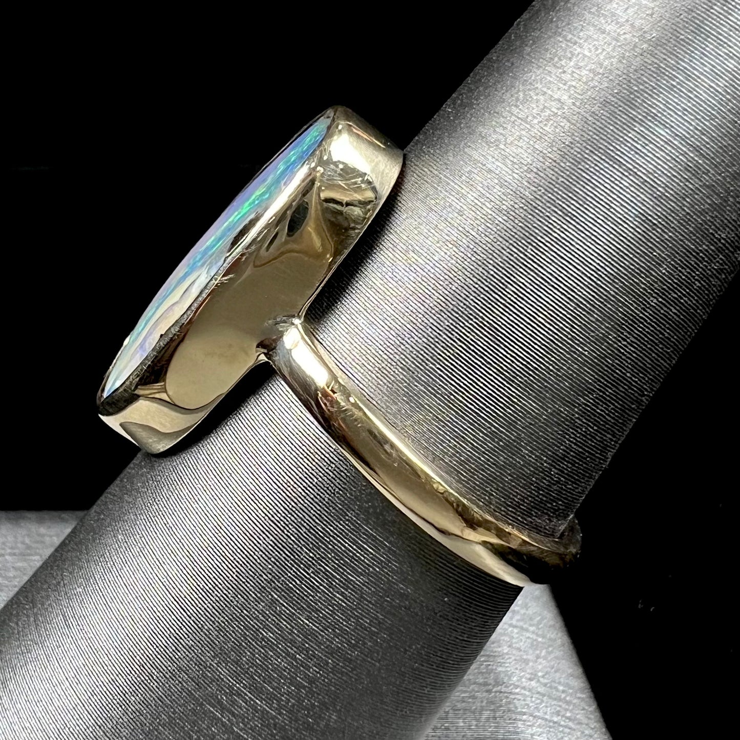 Ladies' yellow gold solitaire ring bezel set with a natural green striped boulder opal from Quilpie, Australia.