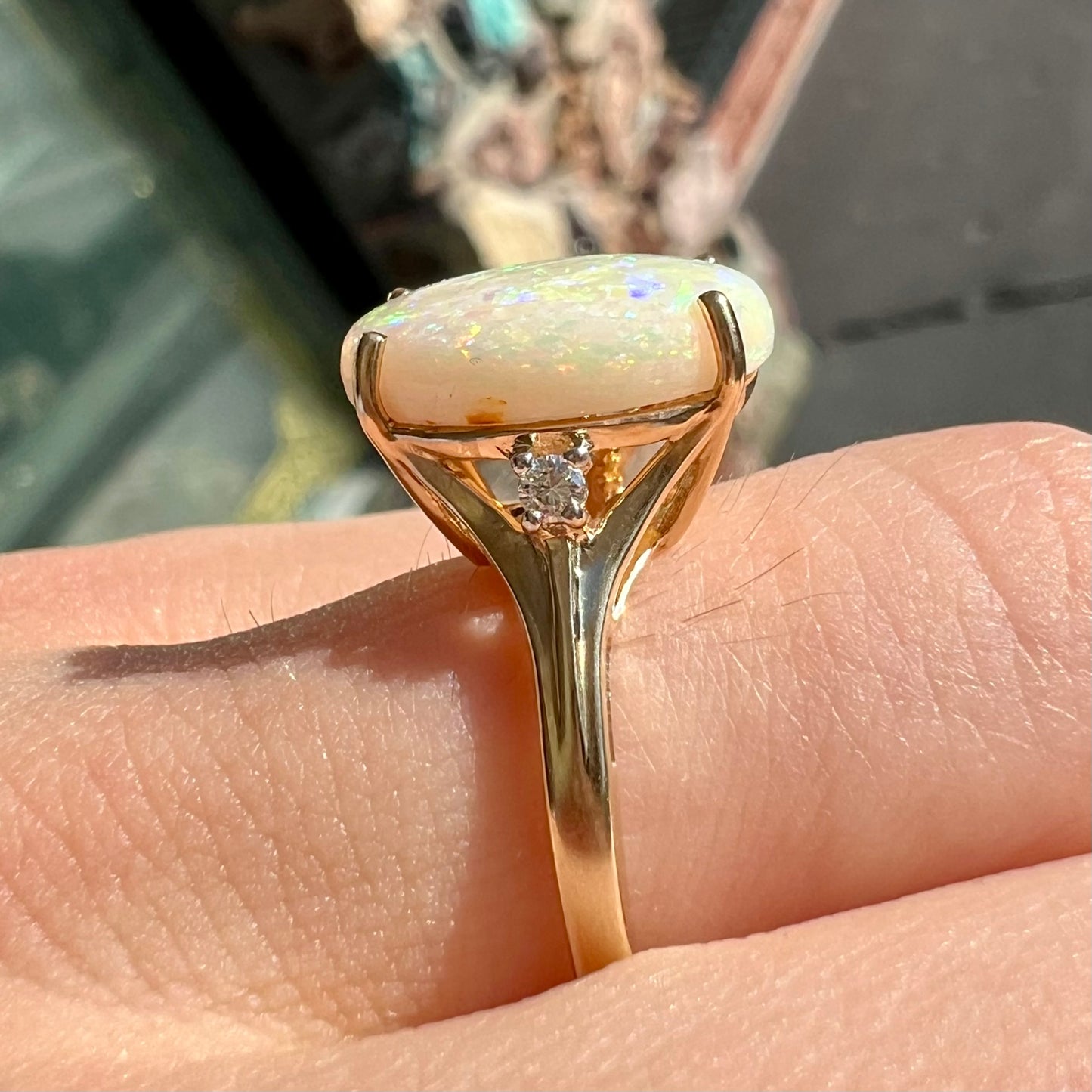A ladies' yellow gold ring set with two diamonds and an oval cut natural opal stone.