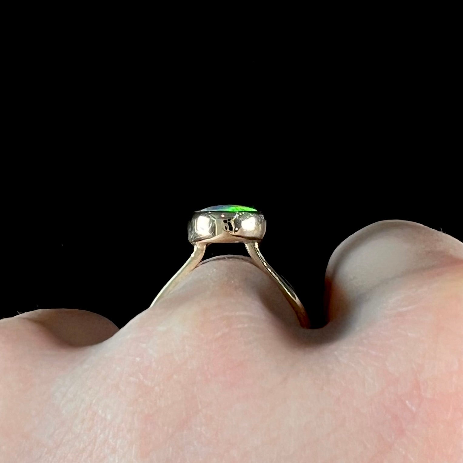 A yellow gold solitaire ring set with a natural Australian cat's eye opal stone.