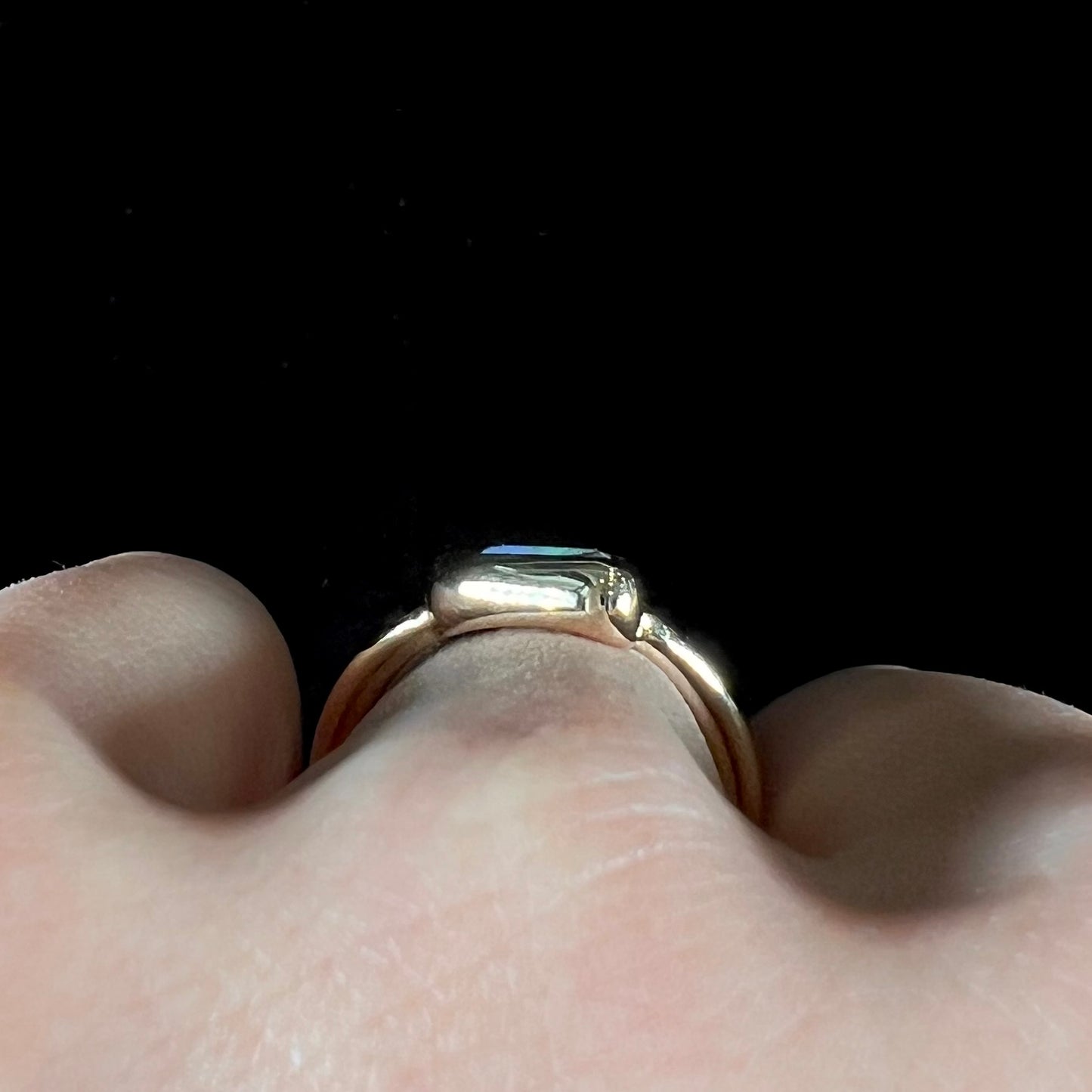 A ladies' split shank gold ring bezel set with a natural, Australian black boulder opal.