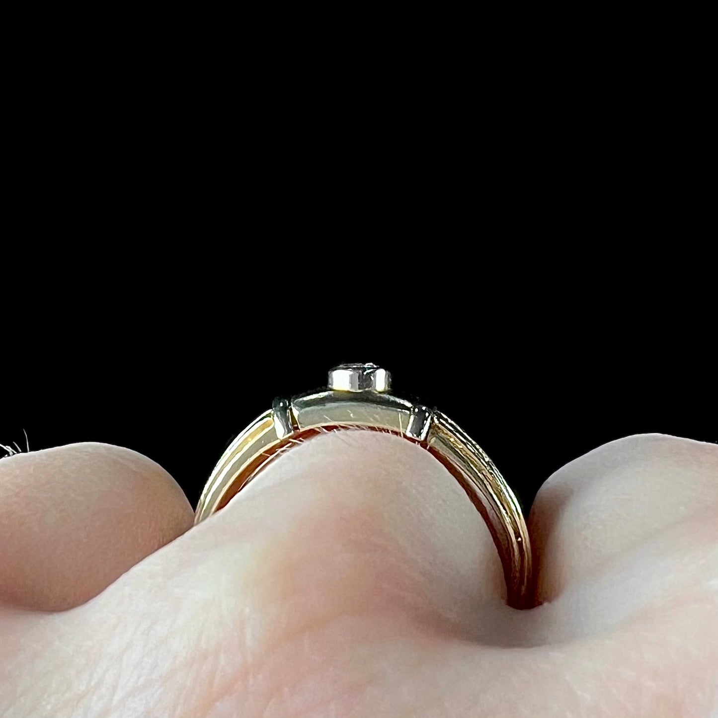 A unisex, vintage style two tone yellow and white gold wedding ring bezel set with a round diamond.