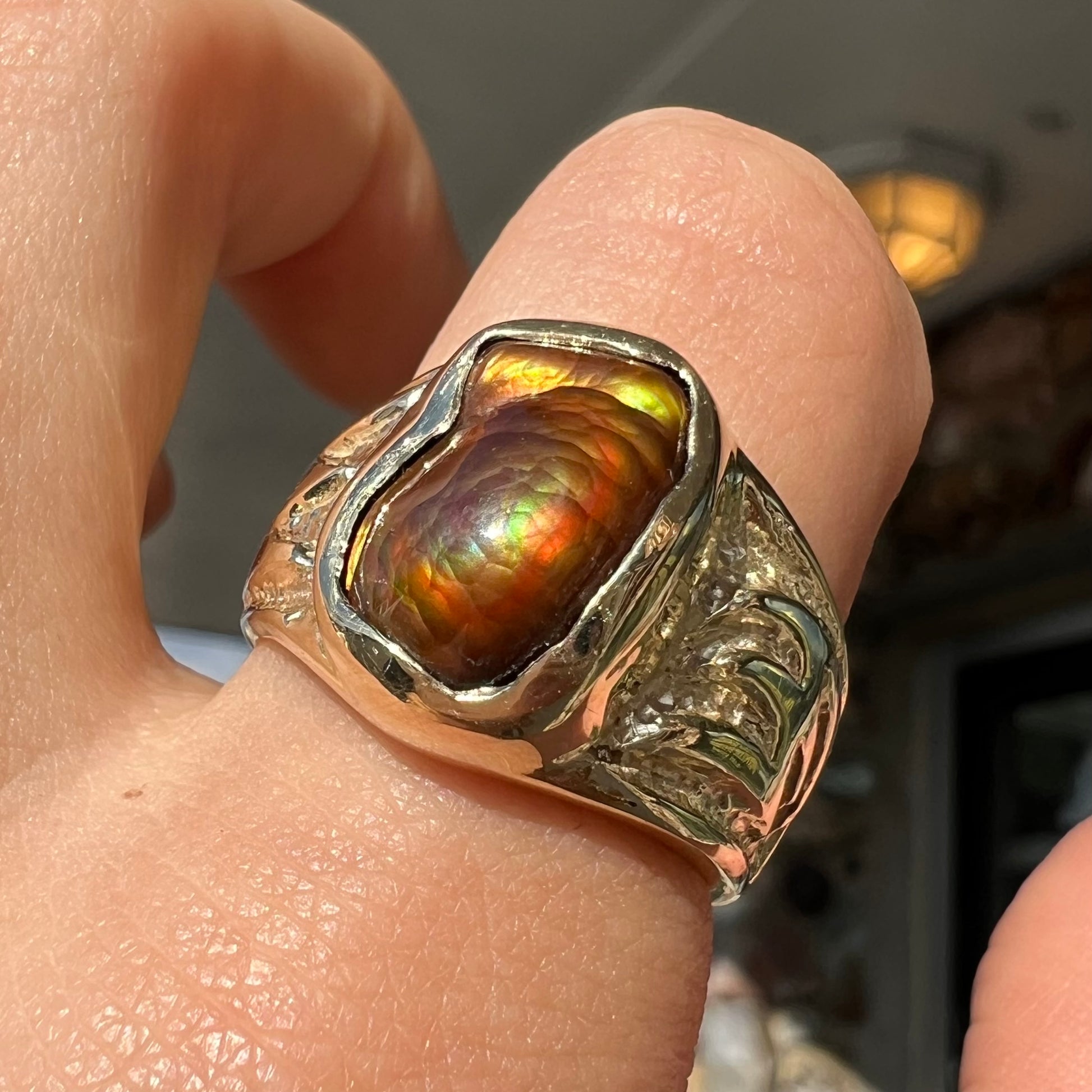 A man's yellow gold solitaire ring set with a freeform shaped Mexican fire agate stone.  The stone has a purple bull's eye pattern.