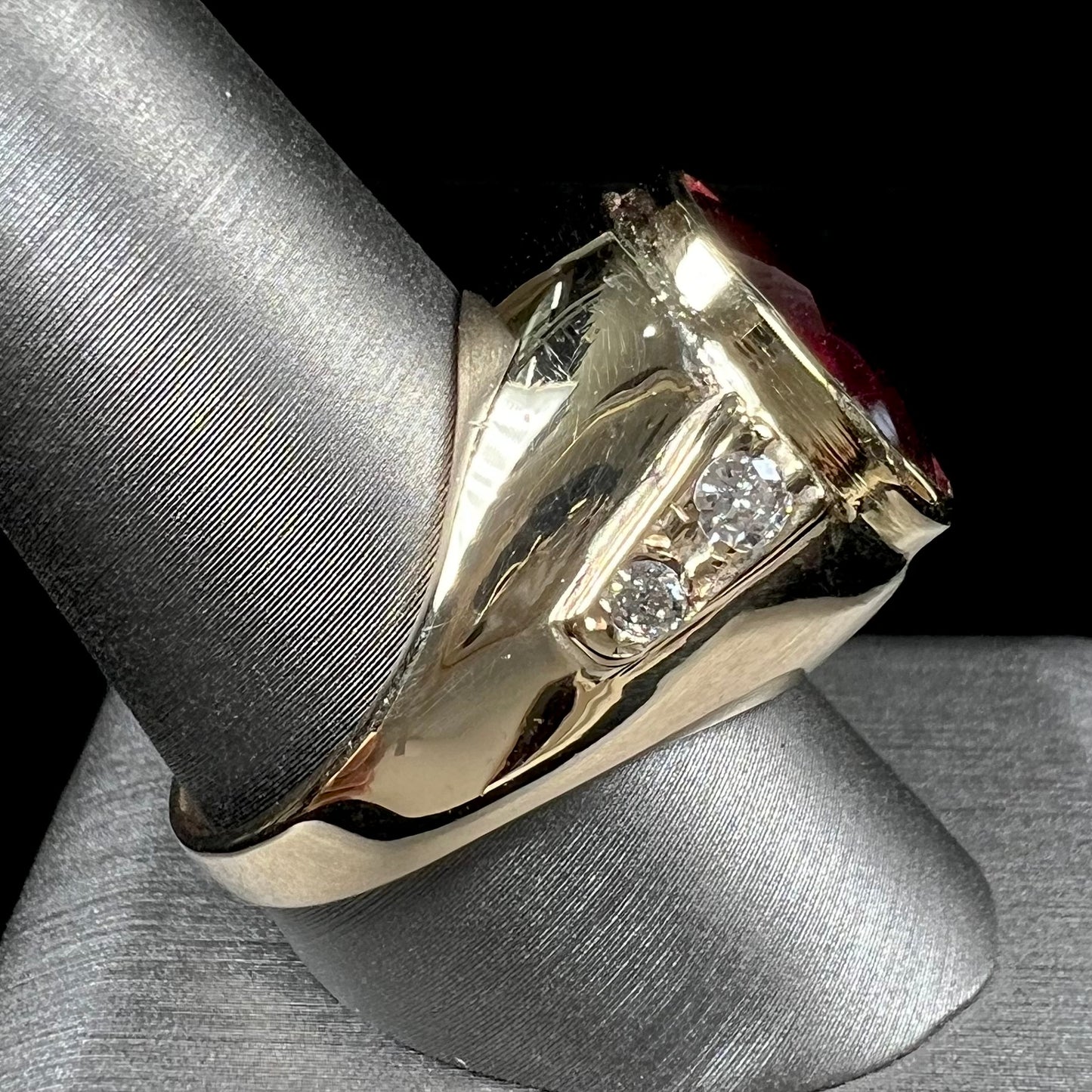 A men's yellow gold ring set with an oval cut rubellite tourmaline with diamond accents.