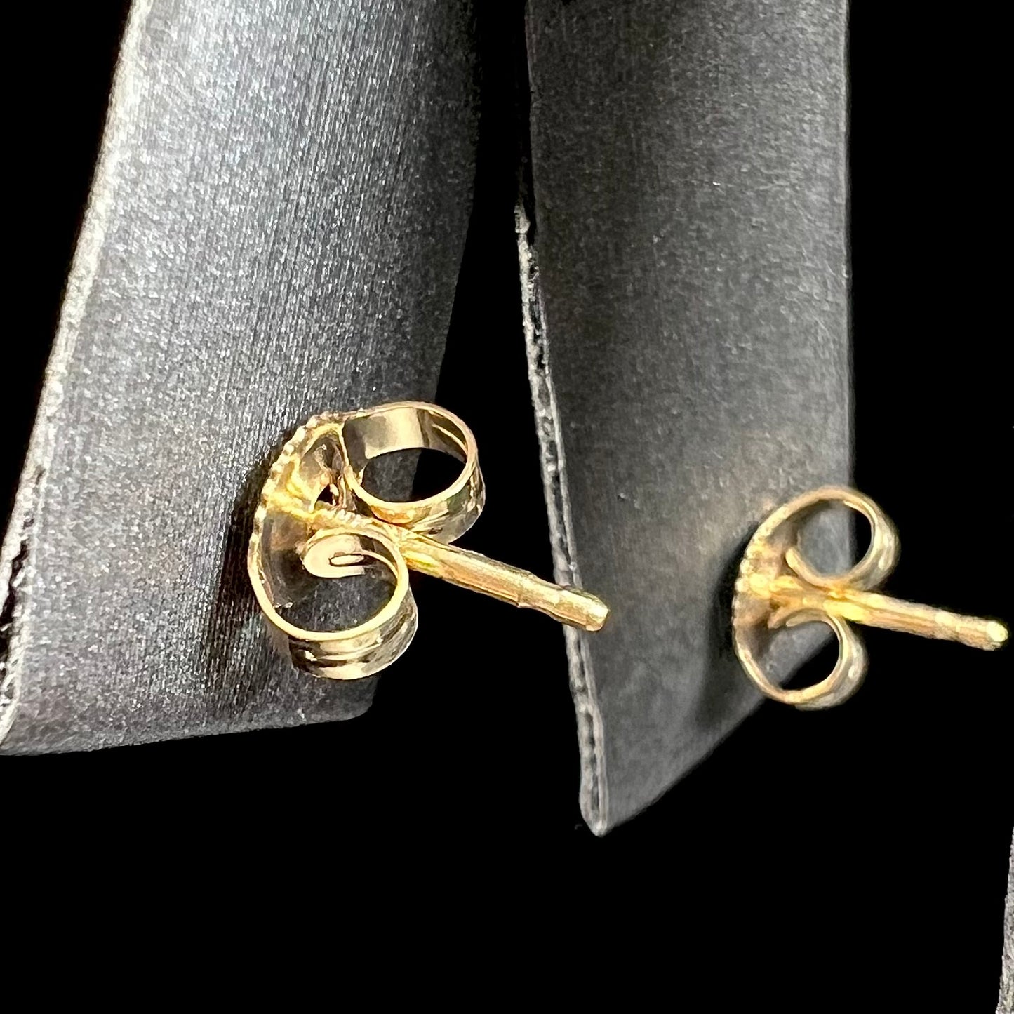A pair of yellow gold stud earrings set with pinkish red Burmese rubies. The rubies are emerald cut.