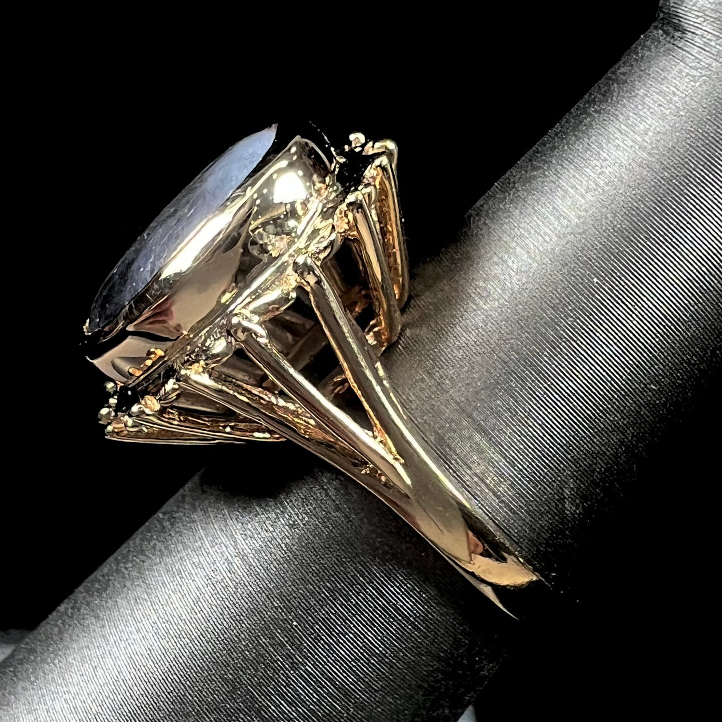 A ladies' yellow gold solitaire ring mounted with a gray trapiche star sapphire.