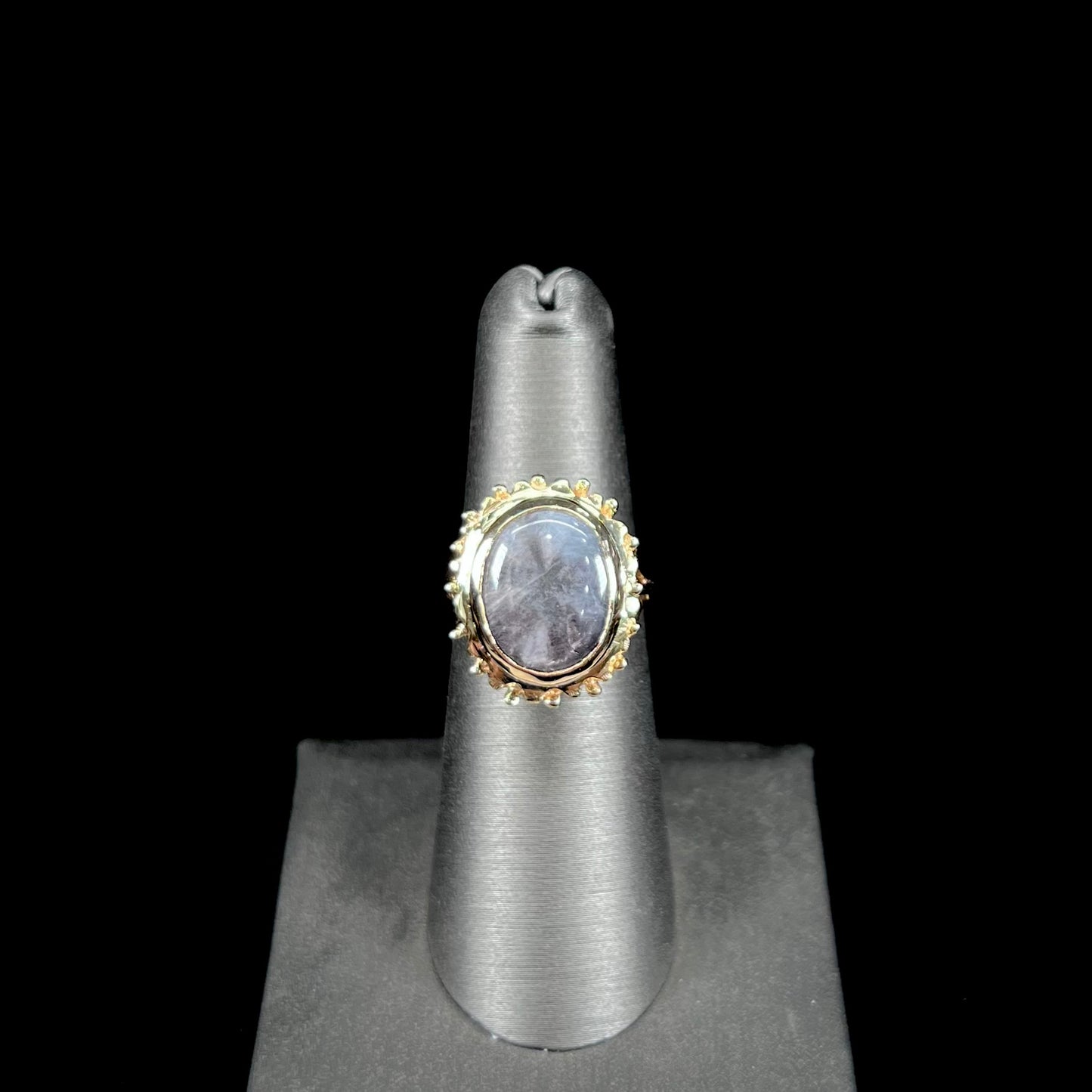 A ladies' yellow gold solitaire ring mounted with a gray trapiche star sapphire.