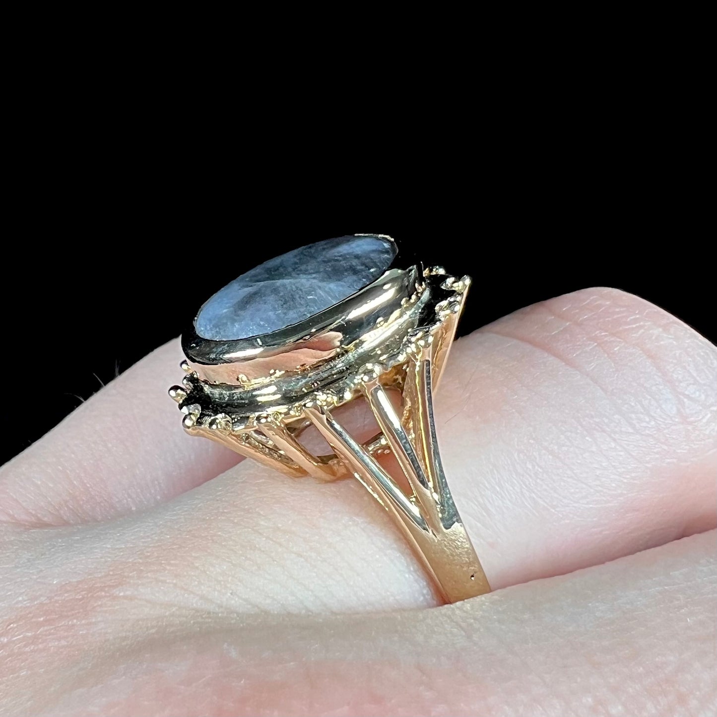 A ladies' yellow gold solitaire ring mounted with a gray trapiche star sapphire.