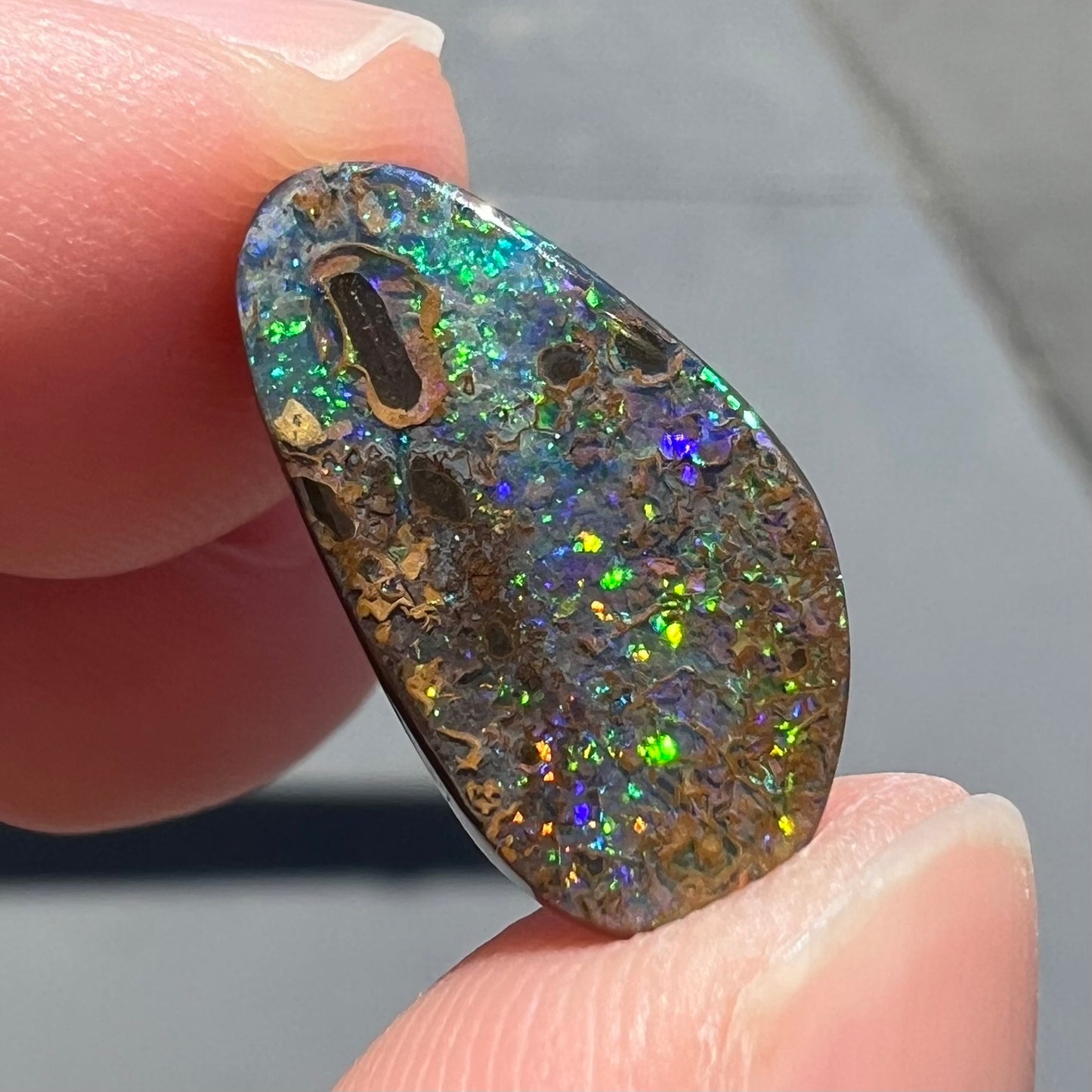 A loose boulder opal stone from Quilpie, Australia. The opal shines colors of green and orange.