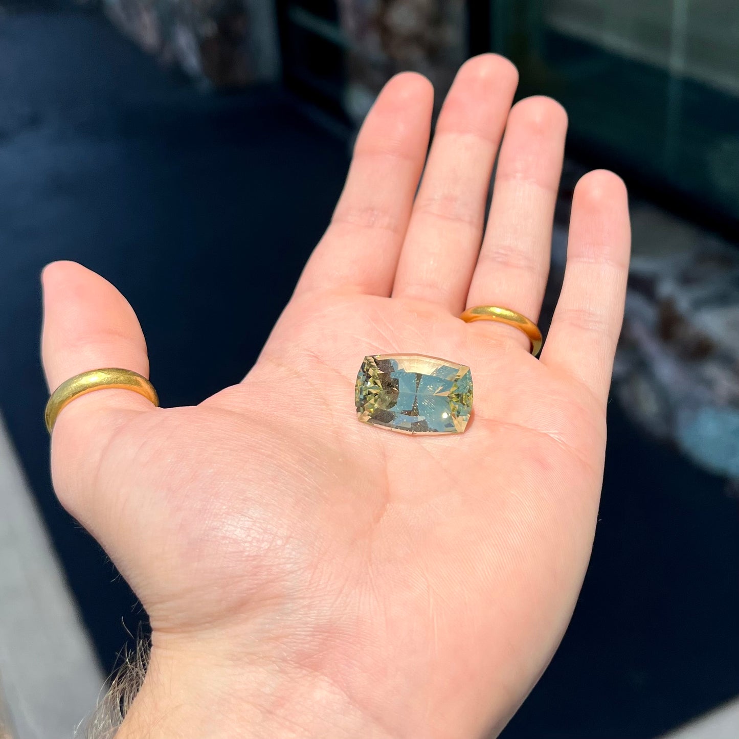 A loose, modified cushion cut heliodor beryl gemstone. The stone is a yellow-green color.