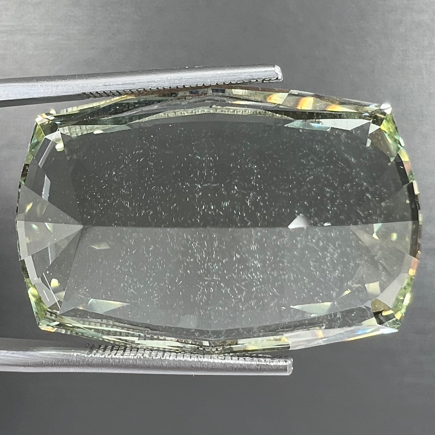 A loose, modified cushion cut heliodor beryl gemstone. The stone is a yellow-green color.