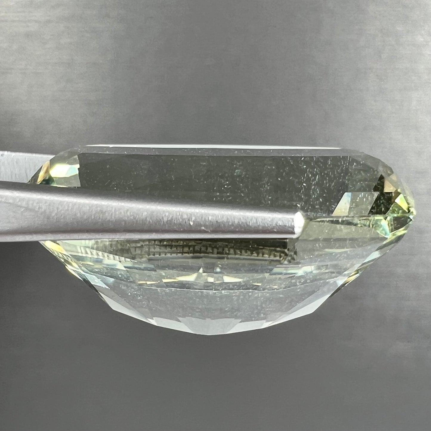 A loose, modified cushion cut heliodor beryl gemstone. The stone is a yellow-green color.