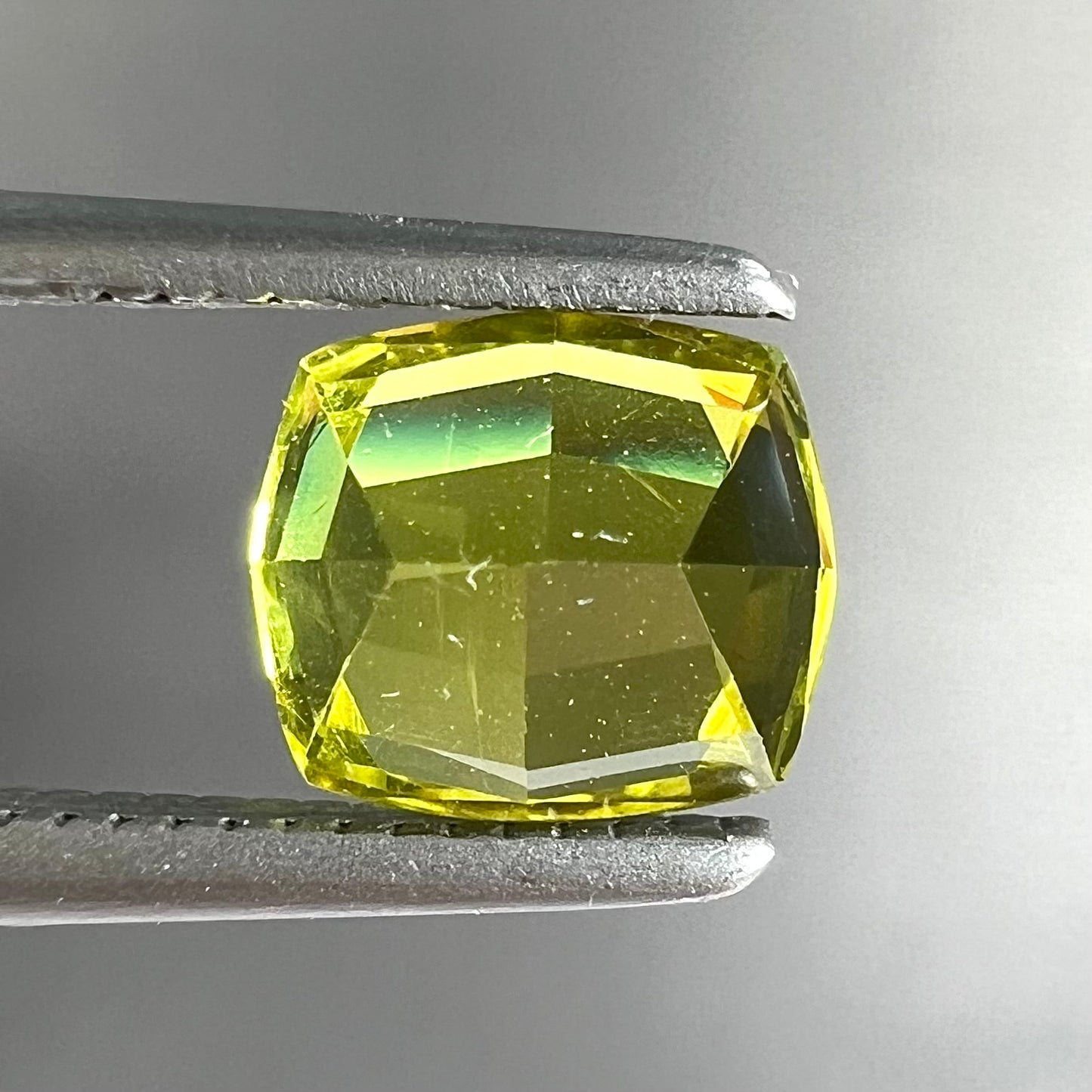 A loose, modified cushion cut greenish yellow chrysoberyl gemstone.