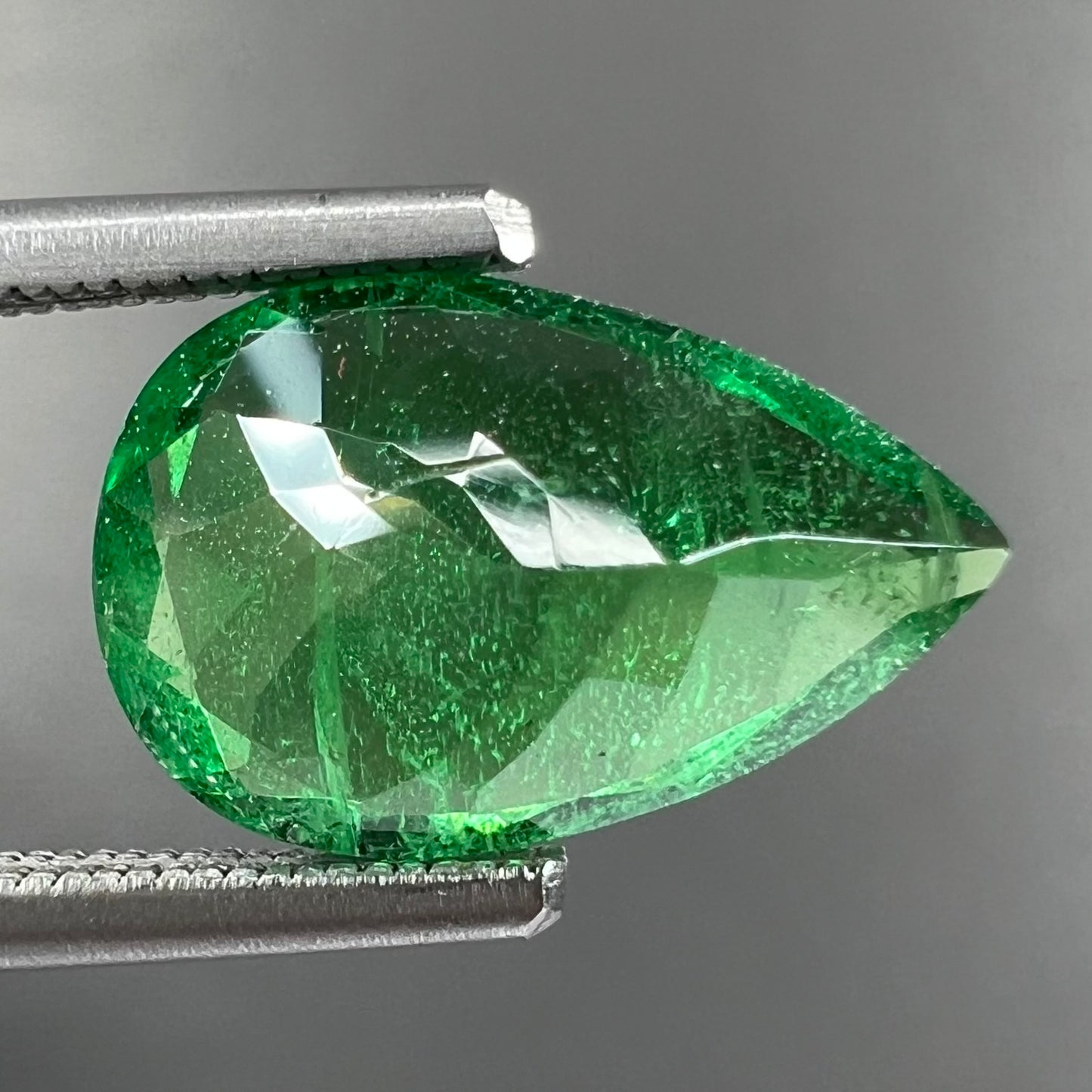 A loose, pear shaped tsavorite garnet gemstone. The stone is vivid green color.