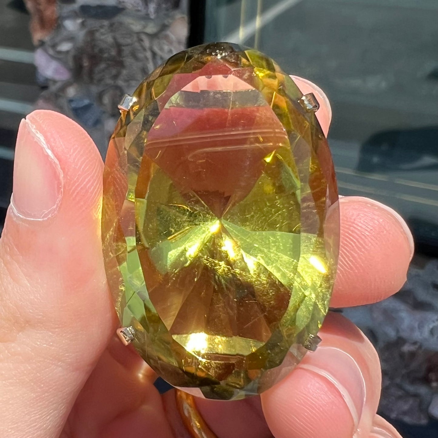 A faceted oval cut lemon quartz gemstone pendant in gold plated sterling silver. The quartz is a green-yellow color.