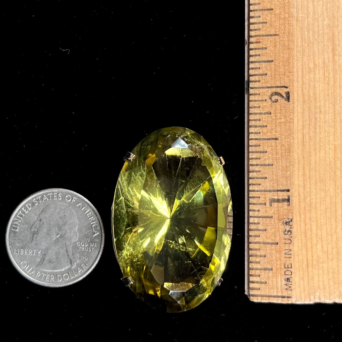 A faceted oval cut lemon quartz gemstone pendant in gold plated sterling silver. The quartz is a green-yellow color.