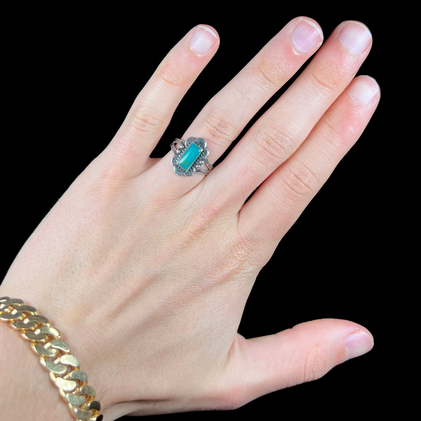 A ladies' silver ring stamped with Southwest style designs and set with a rectangular cabochon cut Royston turquoise stone.