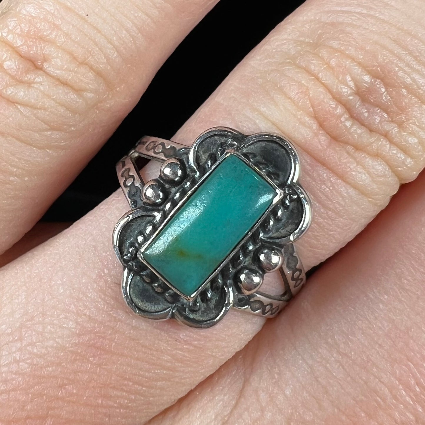 A ladies' silver ring stamped with Southwest style designs and set with a rectangular cabochon cut Royston turquoise stone.