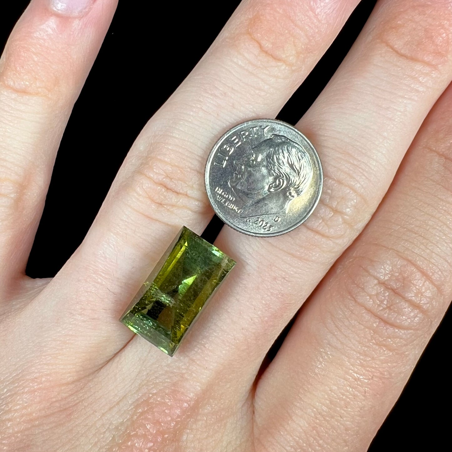 A rectangular step-cut yellowish green tourmaline gemstone.