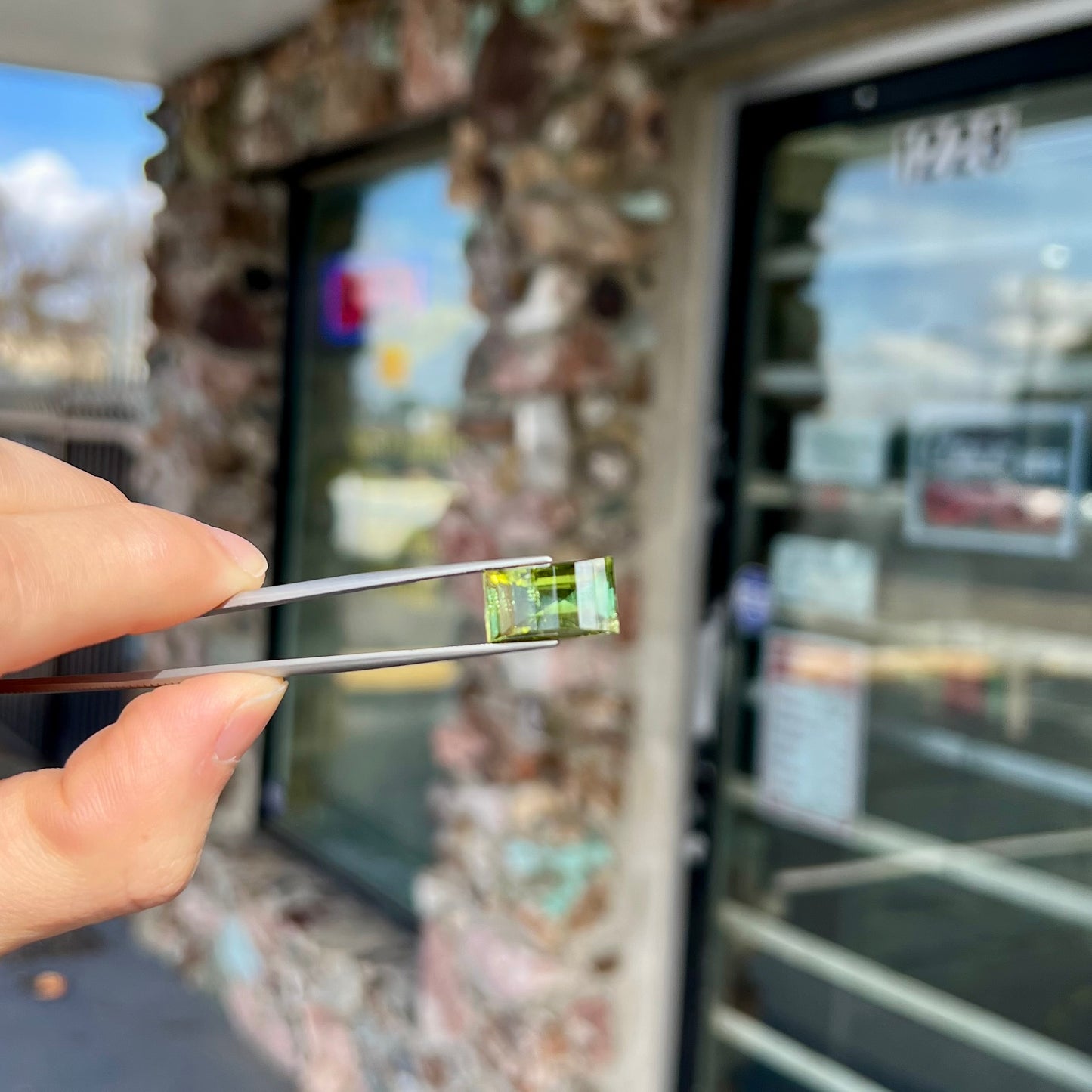 A rectangular step-cut yellowish green tourmaline gemstone.