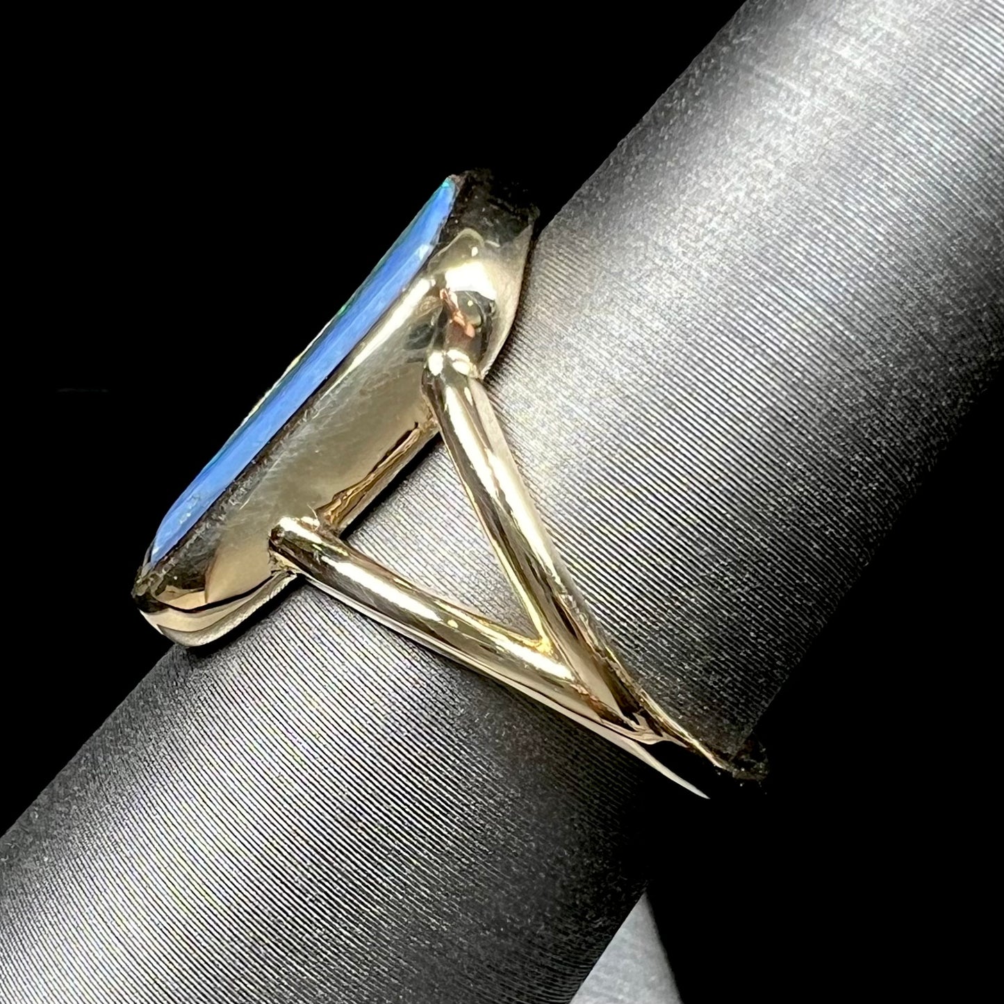 A ladies' split shank gold ring bezel set with a natural, Australian black boulder opal.