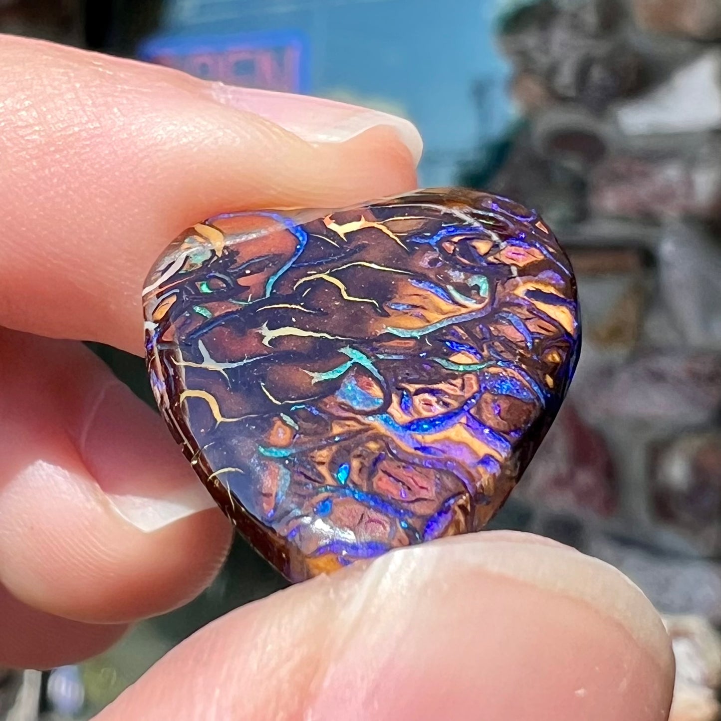 A heart shaped boulder opal stone with purple veins.