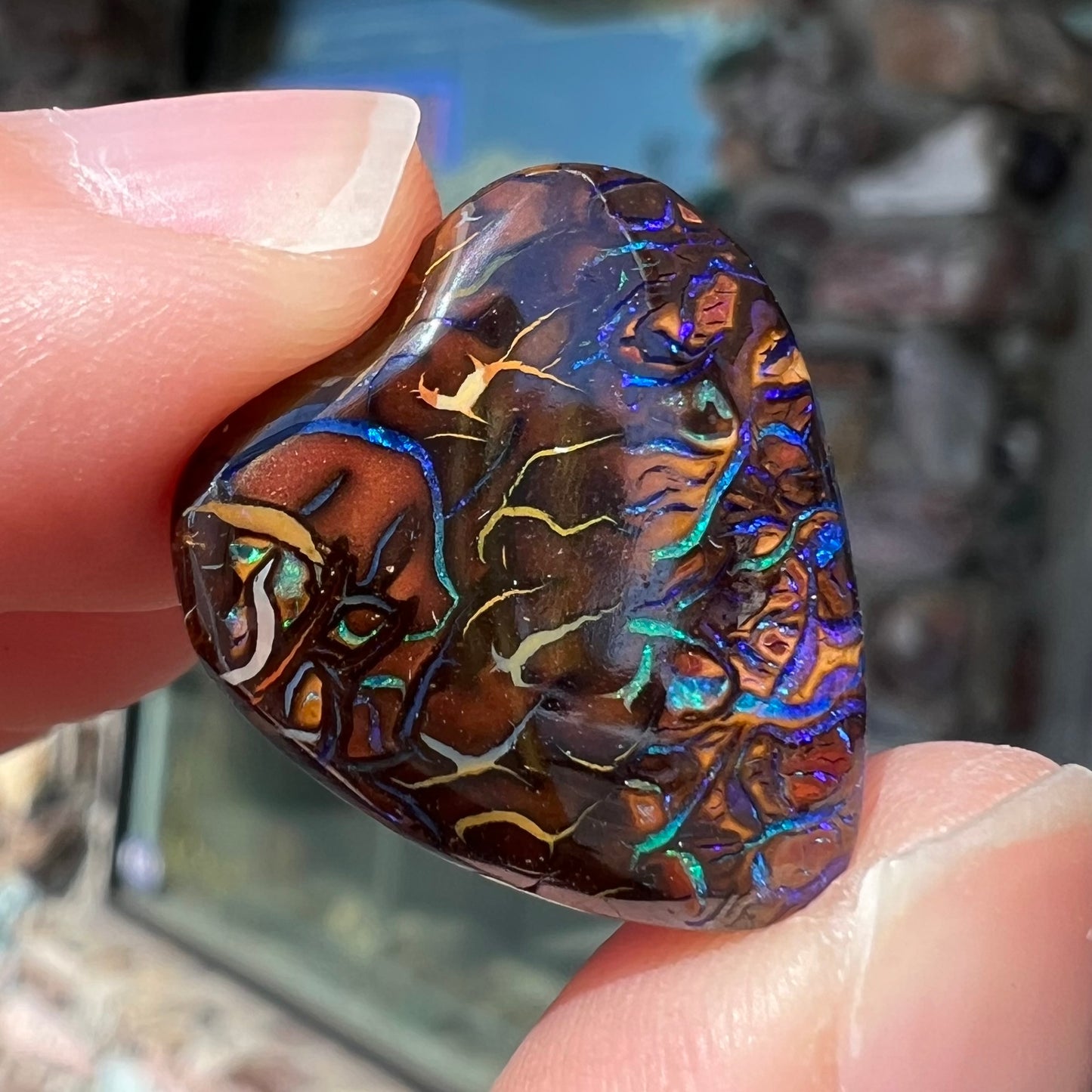 A heart shaped boulder opal stone with purple veins.
