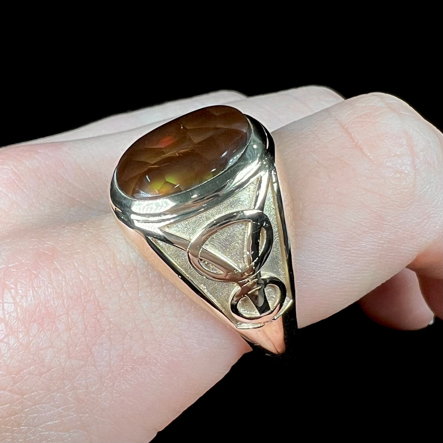 A men's solid yellow gold ring set with a Mexican fire agate stone.  The fire agate has a puple bull's eye pattern.