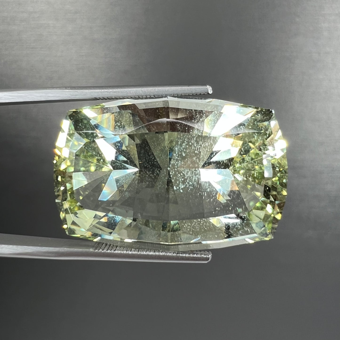 A loose, modified cushion cut heliodor beryl gemstone. The stone is a yellow-green color.