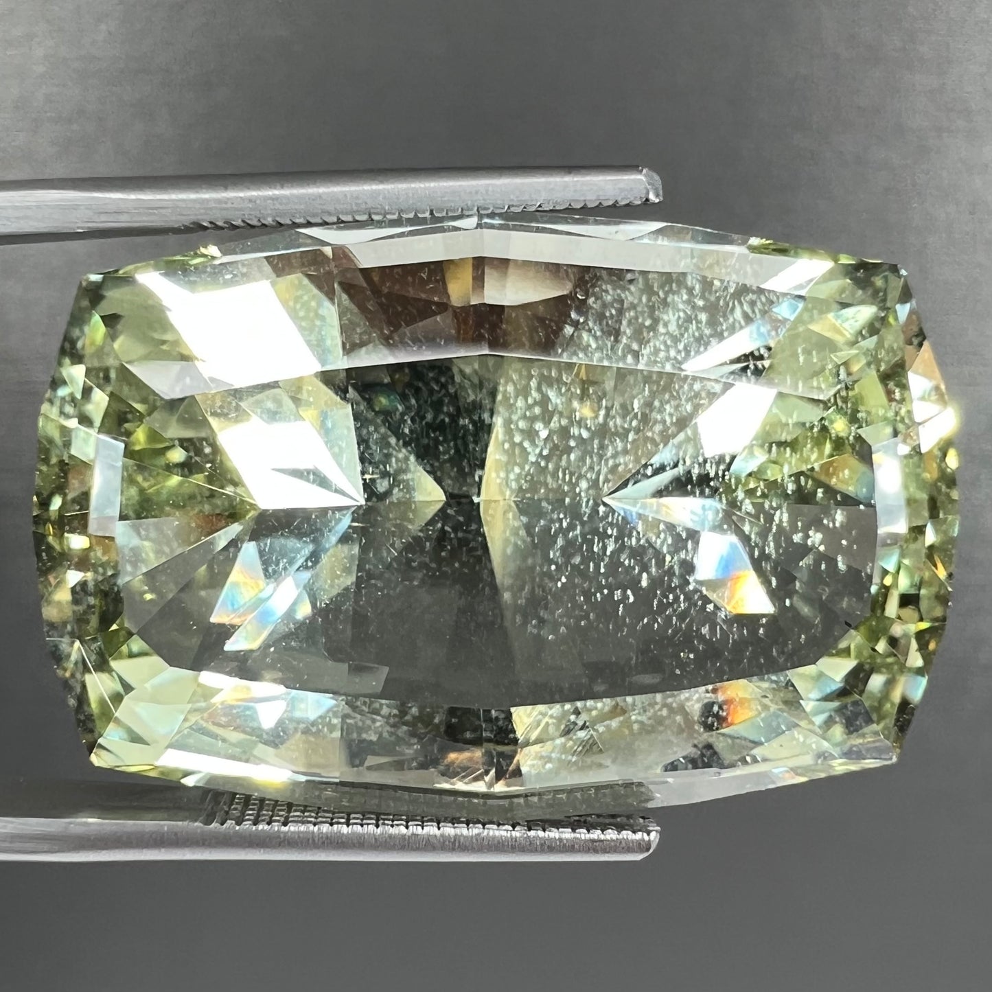A loose, modified cushion cut heliodor beryl gemstone. The stone is a yellow-green color.