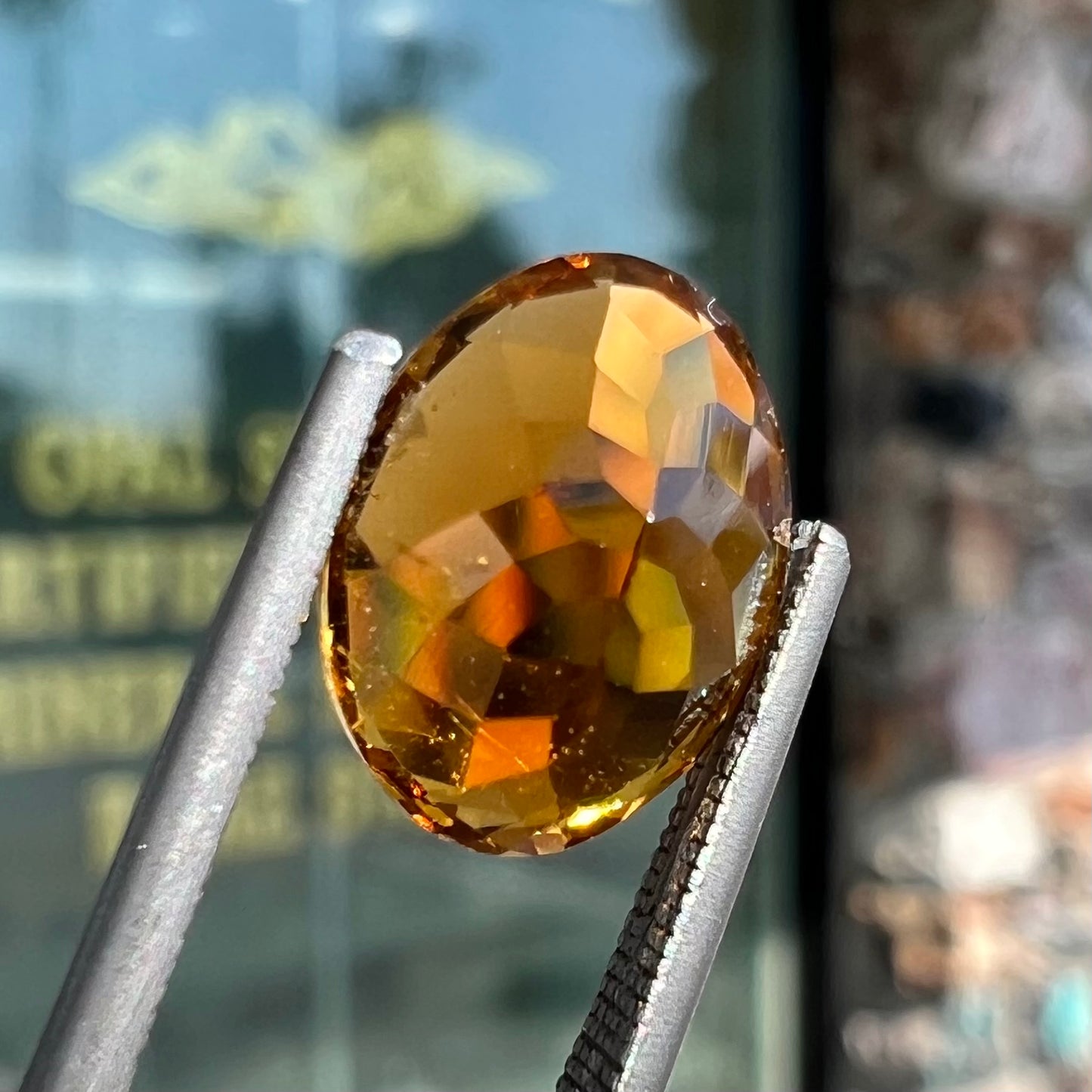 A loose, faceted oval cut orange dravite tourmaline gemstone.