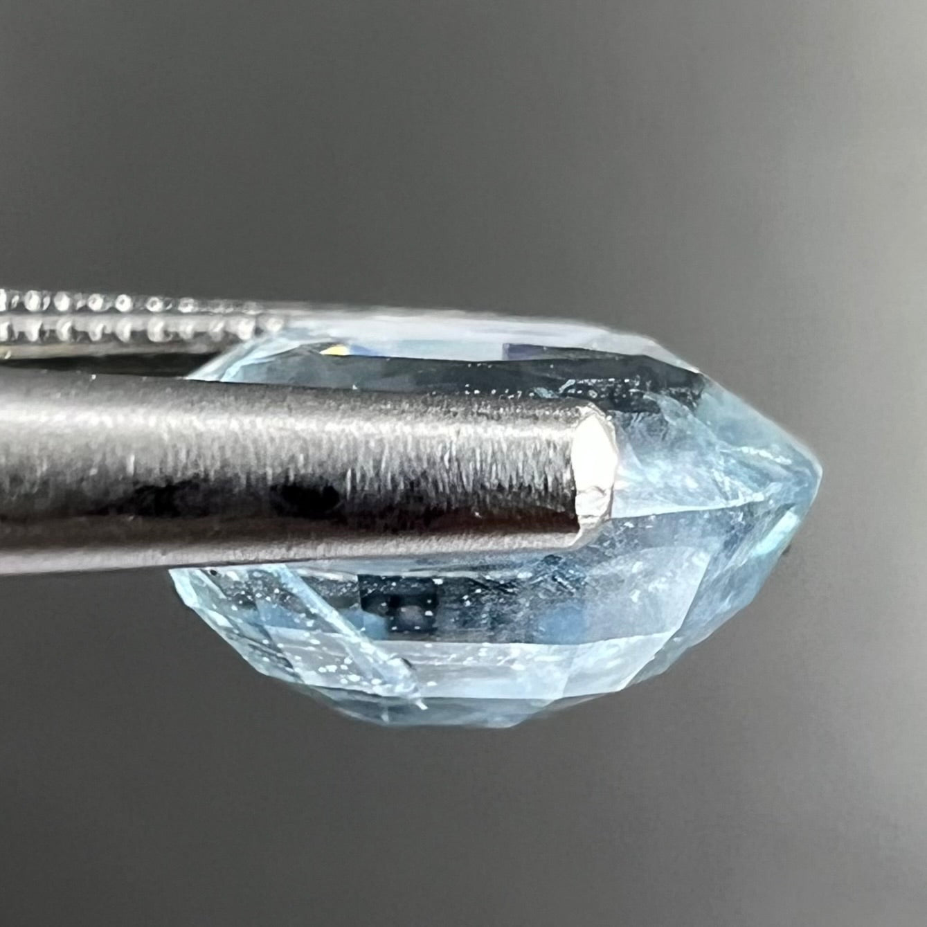A loose, faceted oval cut light blue natural sapphire gemstone.
