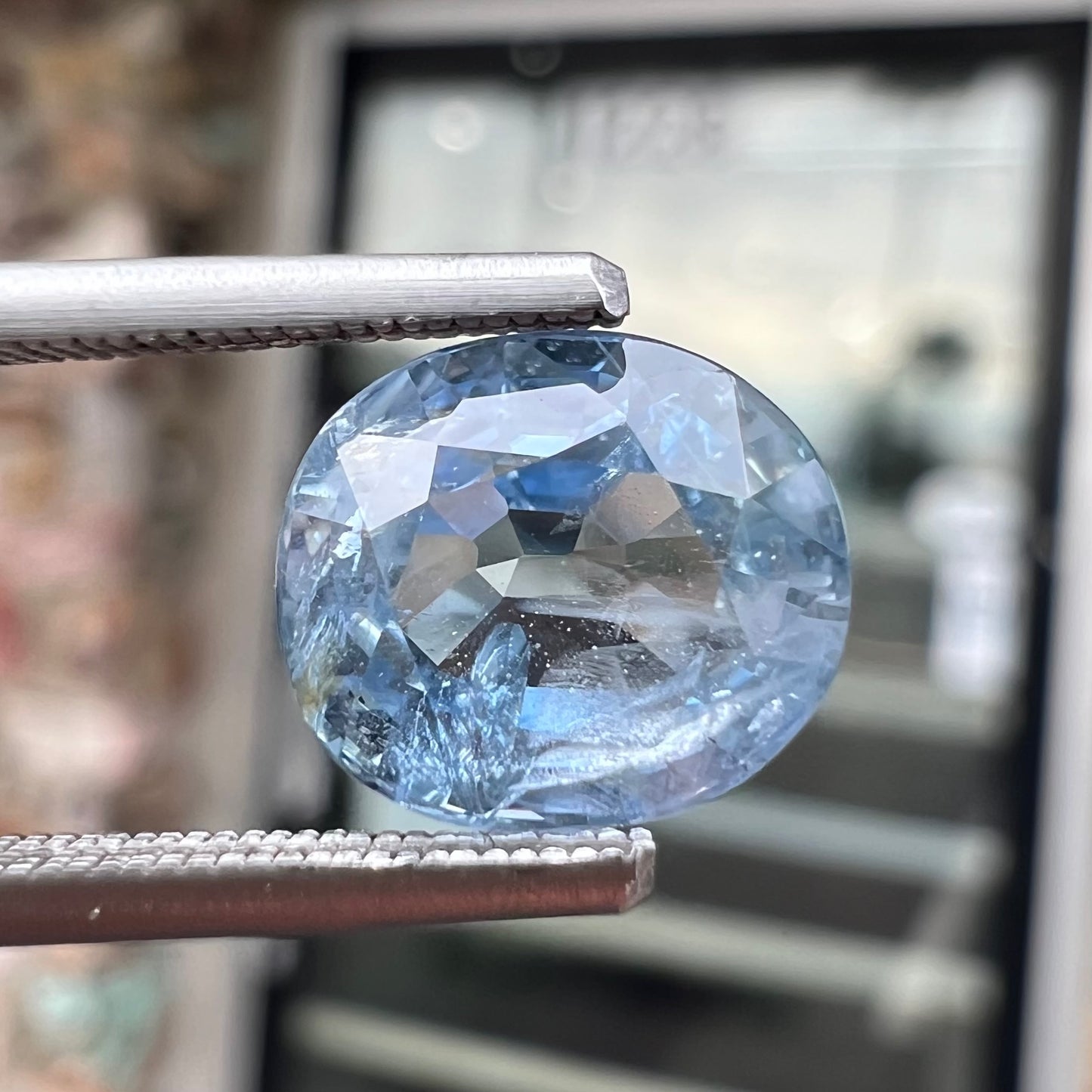 A loose, faceted oval cut light blue natural sapphire gemstone.